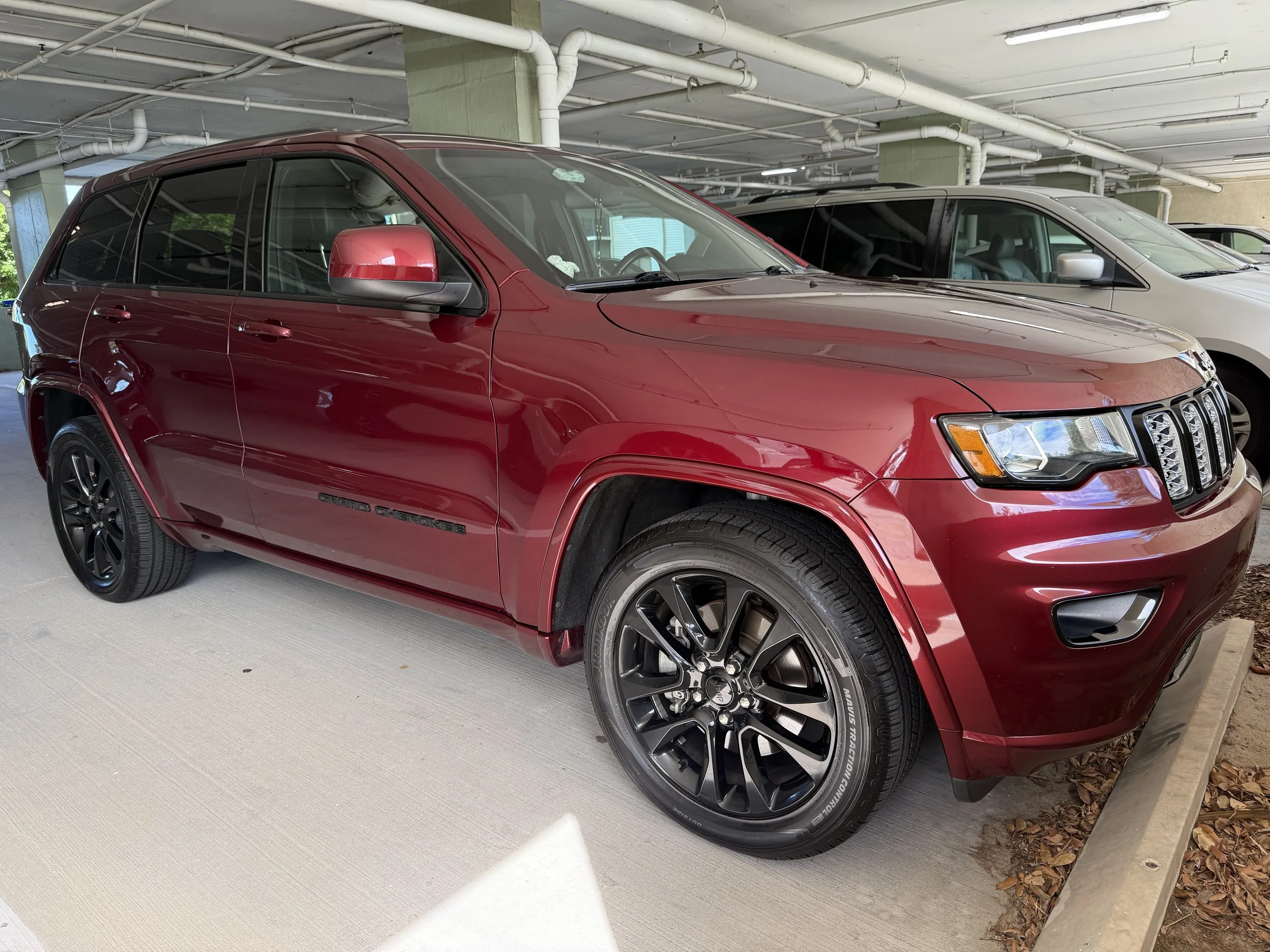 Red Jeep Grand Cherokee parked in an indoor parking garage.