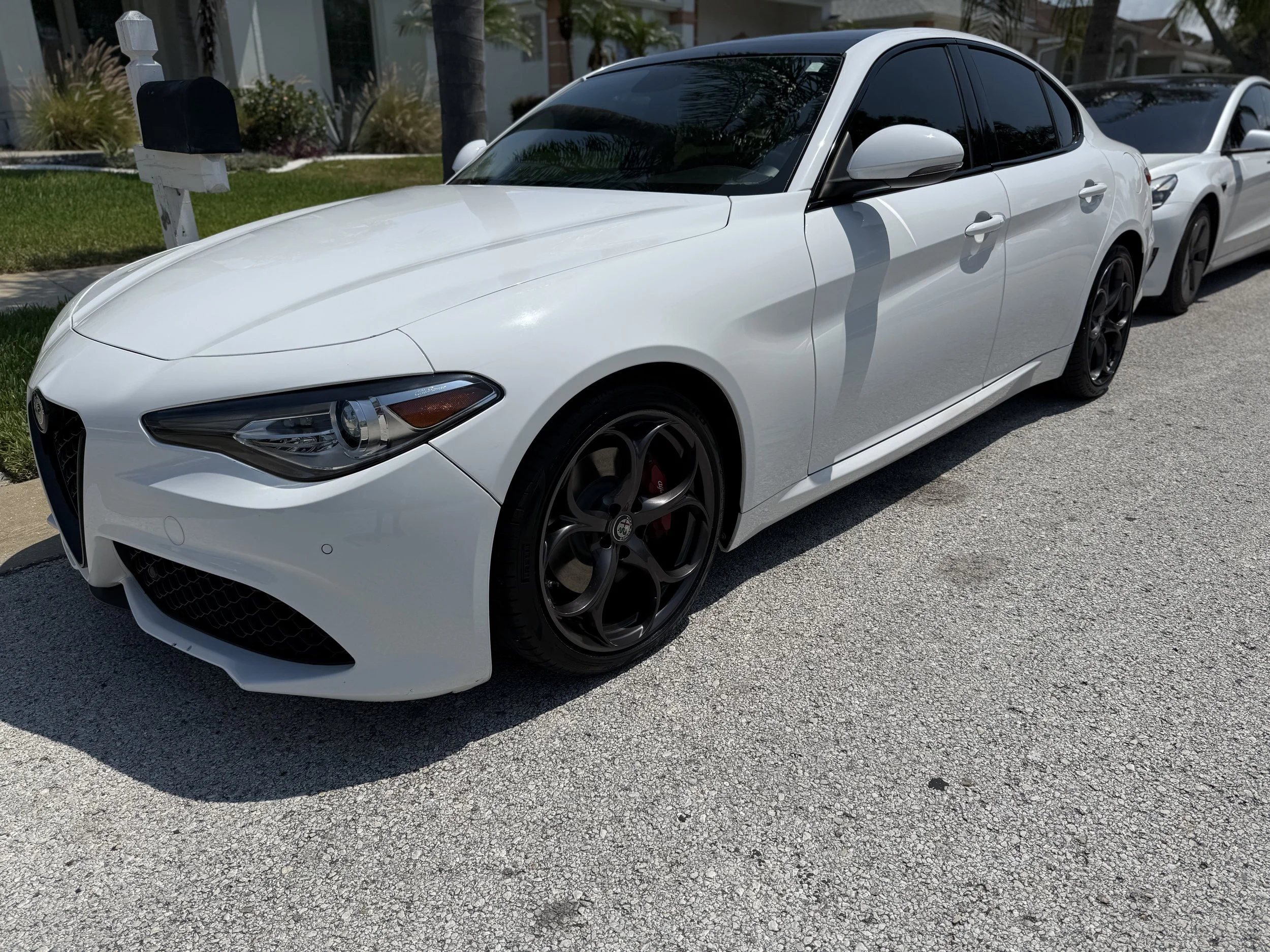 White luxury sports sedan parked on the street with tinted windows and black wheels.