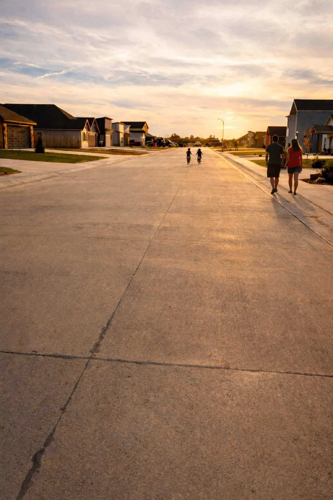 Residential neighborhood street with homes and people walking and biking.