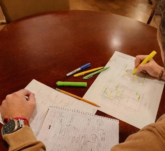 Person reviewing architectural plans at a work table.