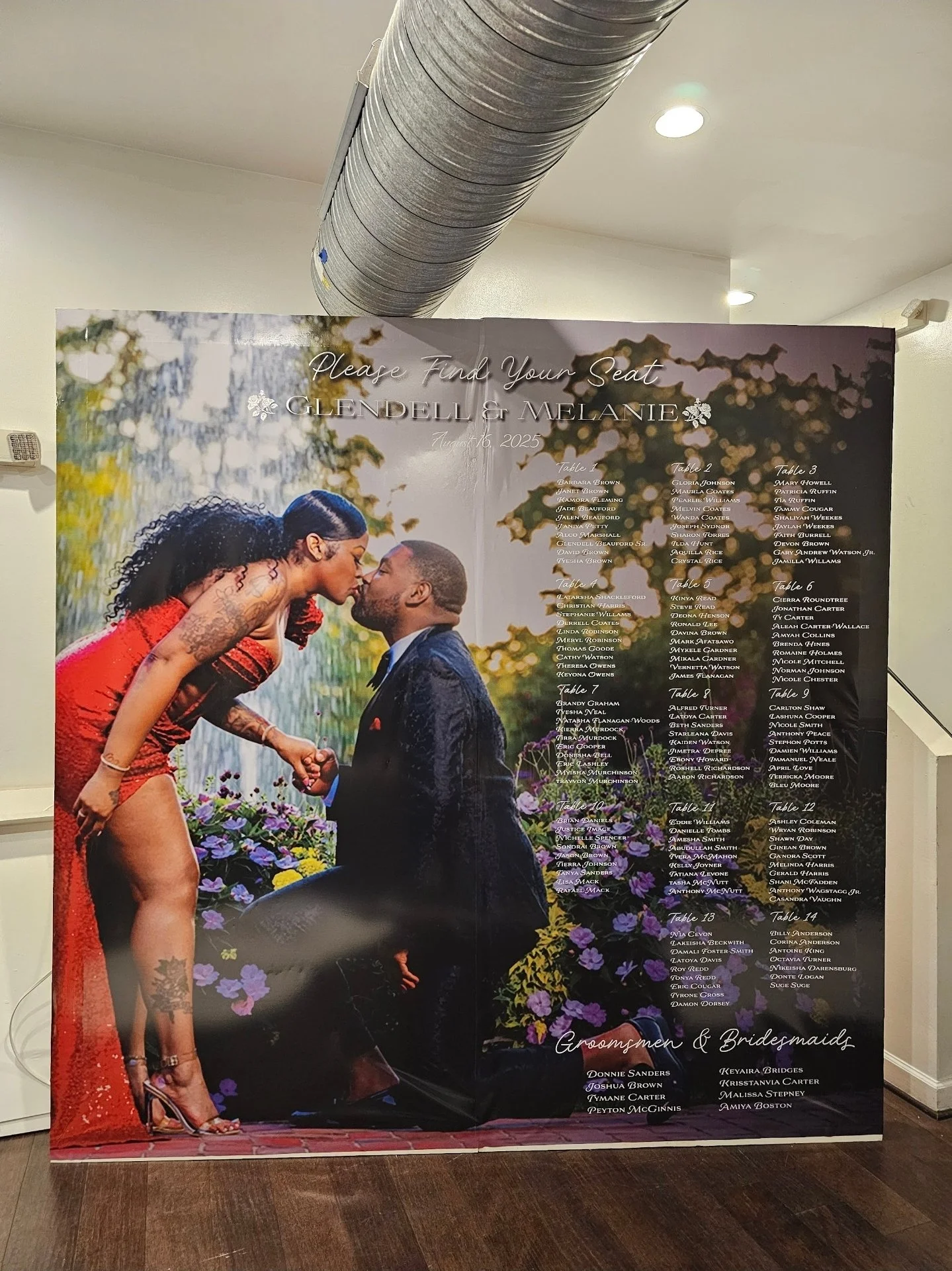 Wedding page with a photo of a bride and groom, surrounded by a list of tables and guests' names. The backdrop has trees and flowers, with the couple about to kiss.