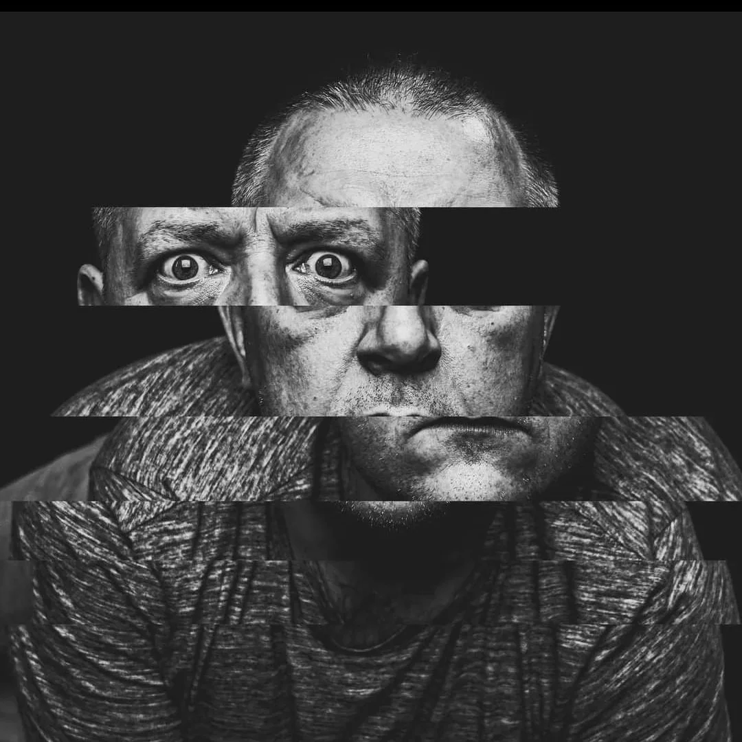 A black and white photo of a man's face with a glitch art effect, creating horizontal strips that are misaligned.