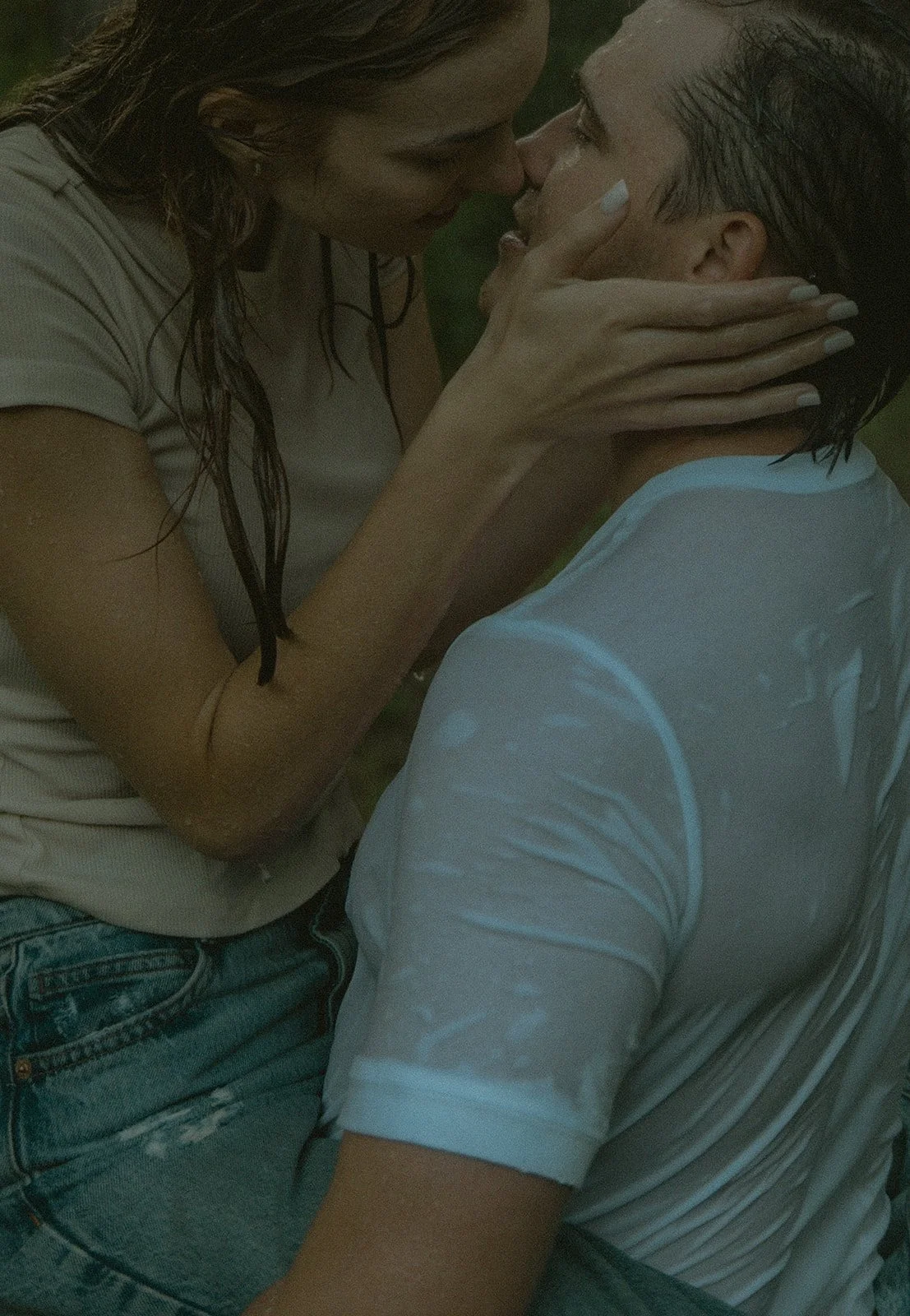 A woman and man are close, about to kiss, with the woman holding the man's face gently.