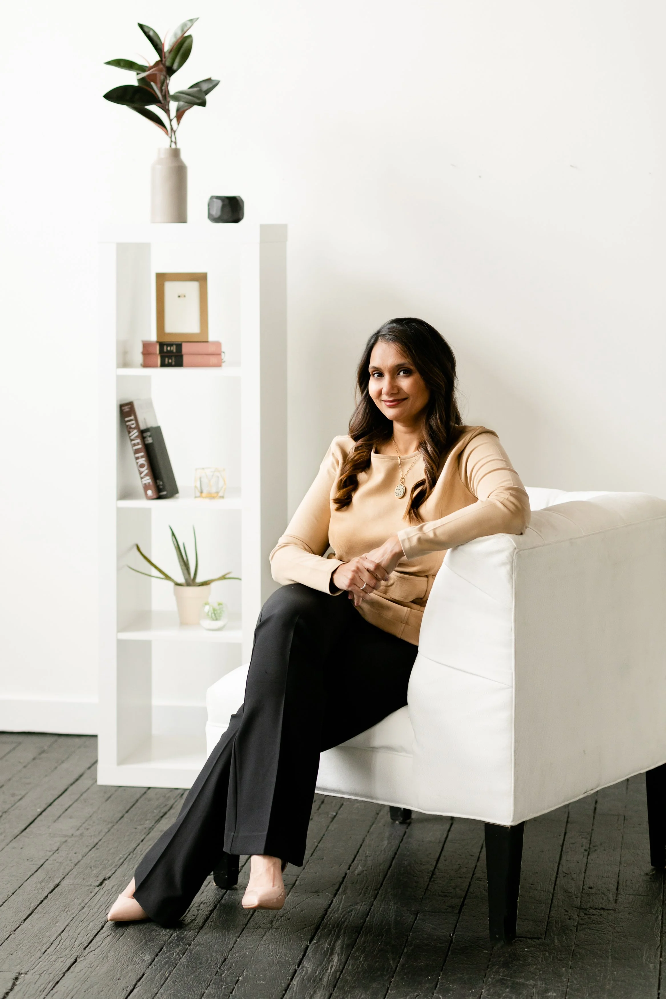 and environmental portrait of a woman sitting in a chair in a staged living room tells the story of a personal brand