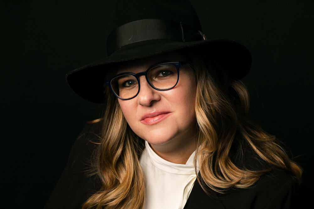 A sophisticated woman business owner wearing black looks at the camera with a half smile