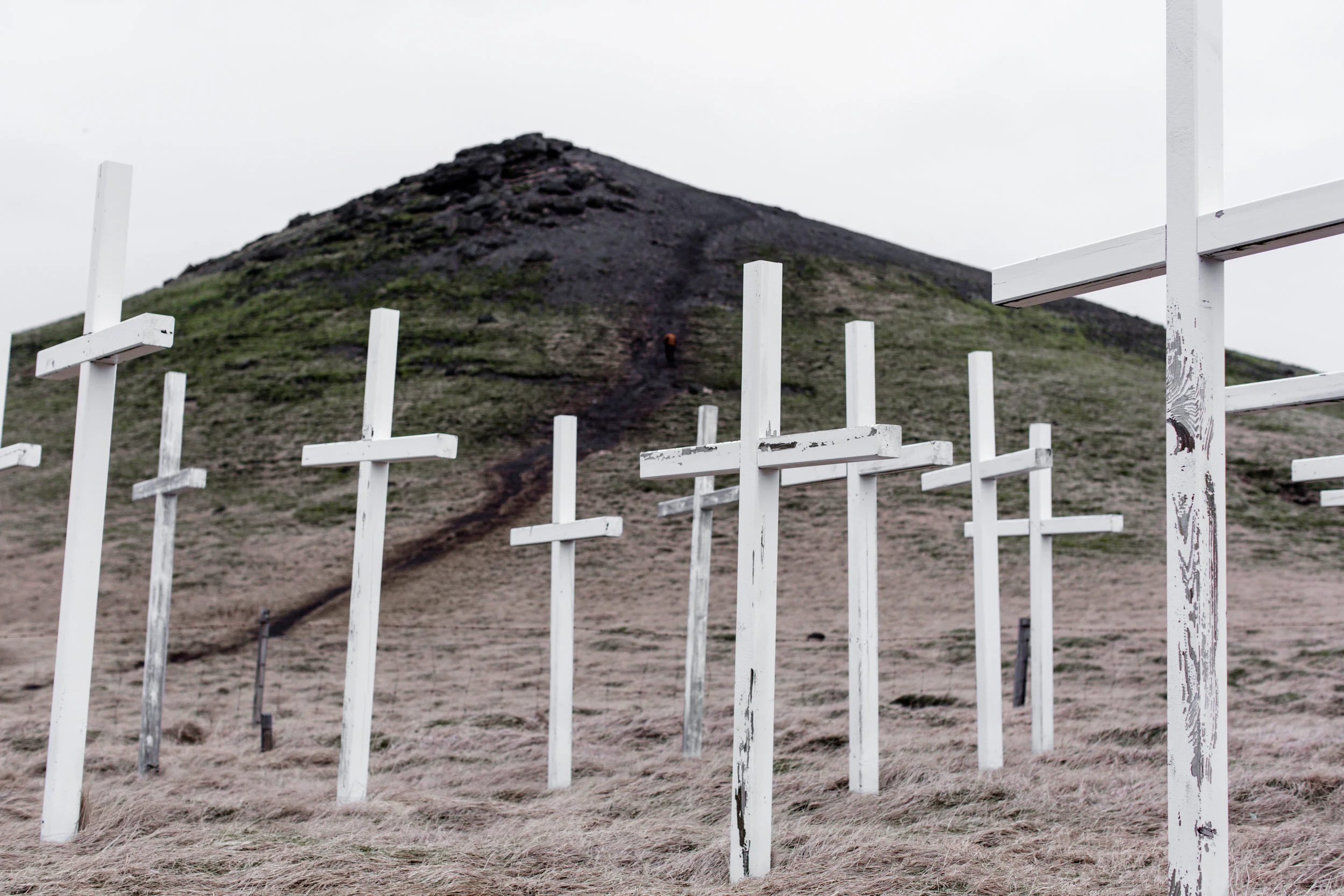 A hillside with a trail and numerous white crosses in the foreground.