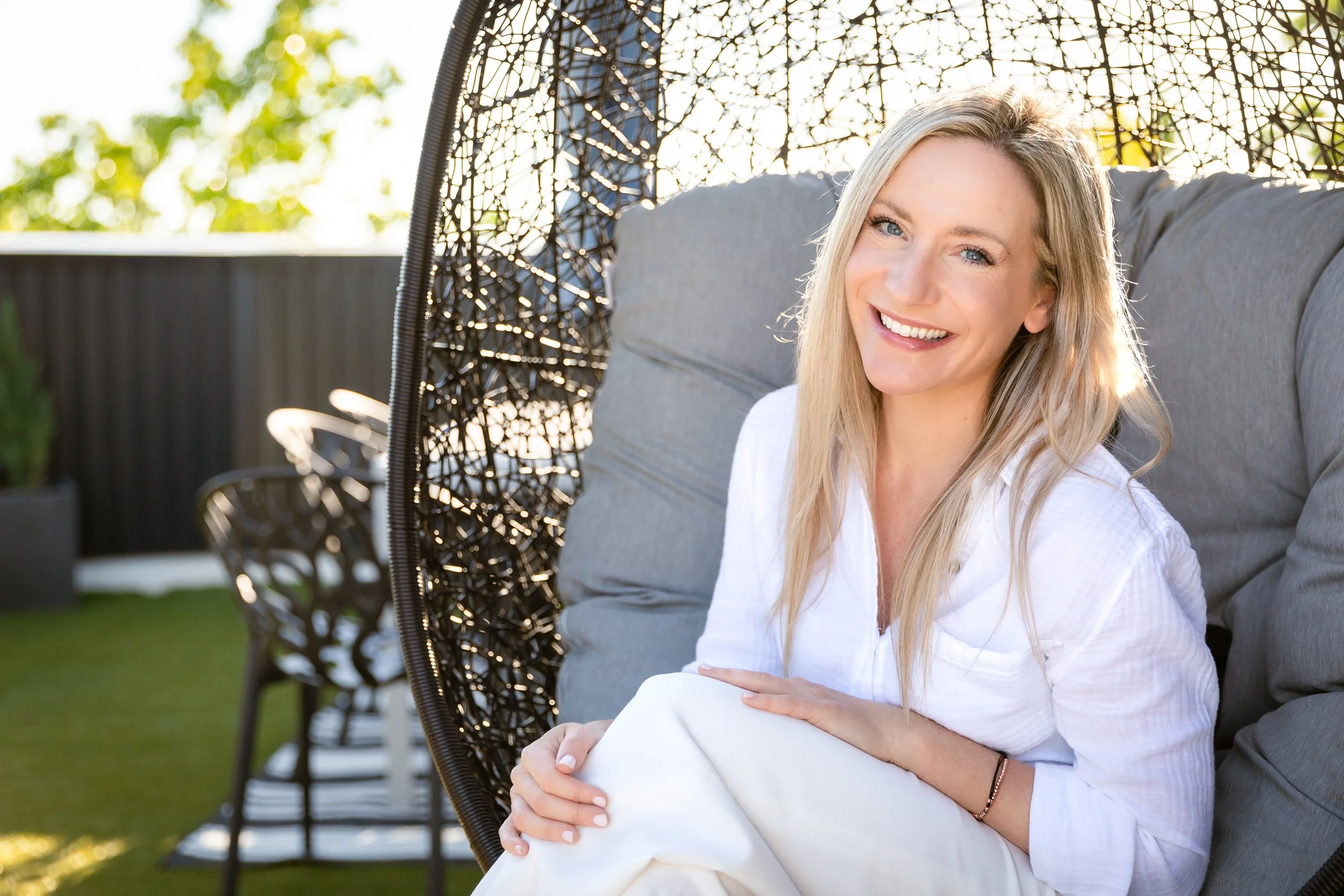 A new real estate agent sits on a hanging rooftop chair on a sunny day 