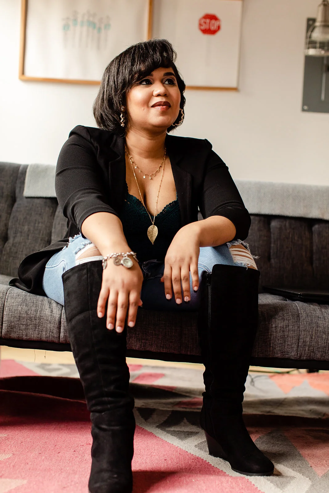 A black woman wearing tall boots poses powerfully to showcase her prowess as a financial coach 