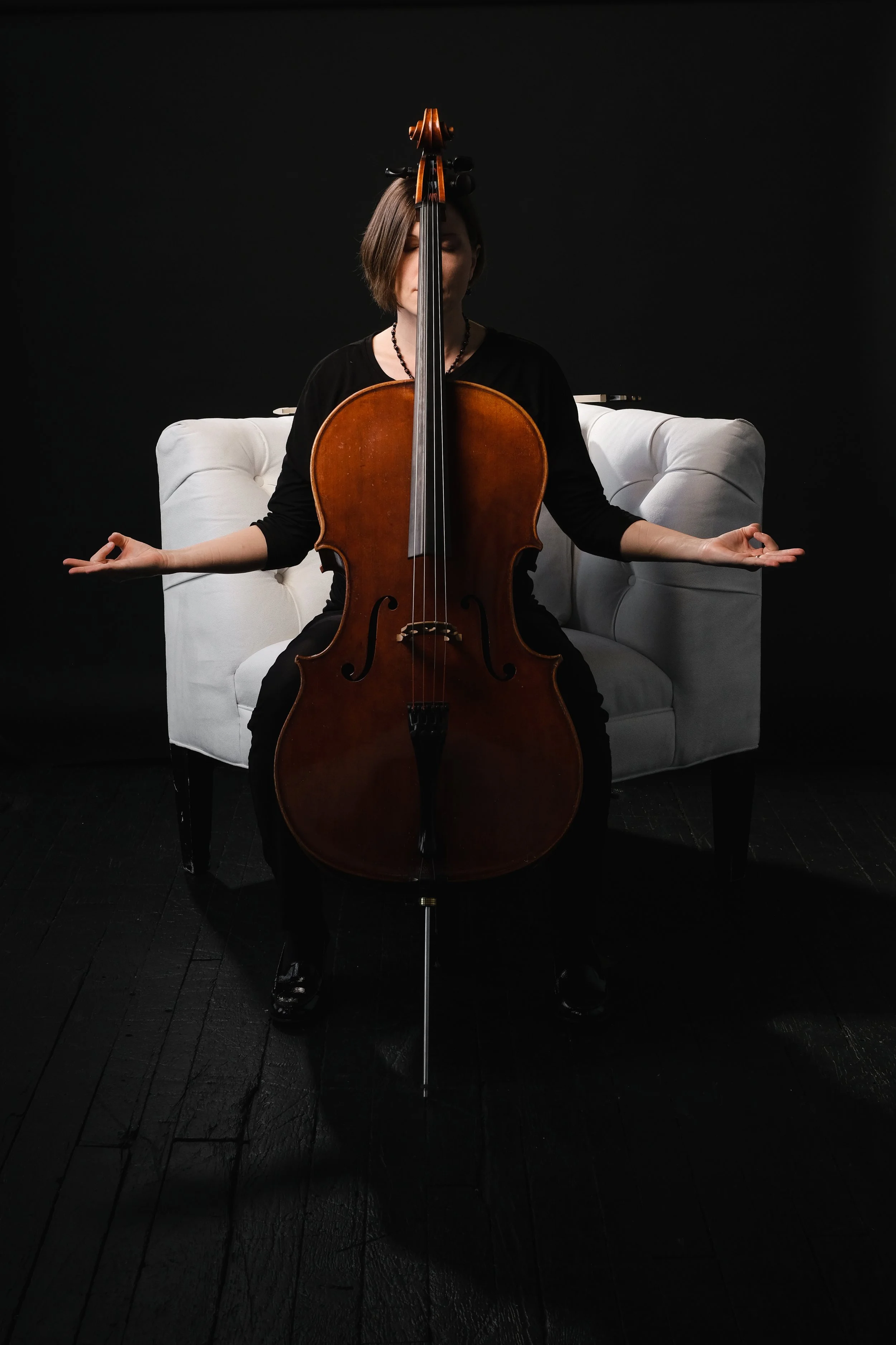 A professional cellist in an orchestra does a yoga pose for her photo shoot while holding her cello