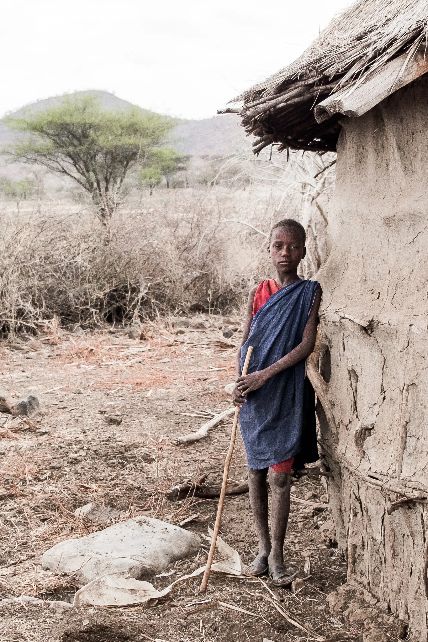 A young Maasai teenager rests against his boma for this photojournalism image