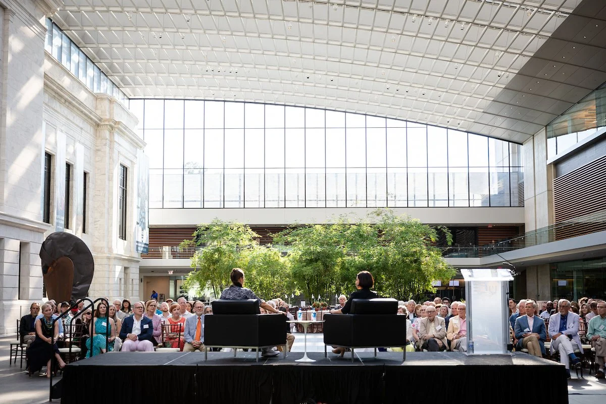A zoomed-out scene in the atrium of a crowd of event attendees listening to an artist speak at the Cleveland Museum of Art 