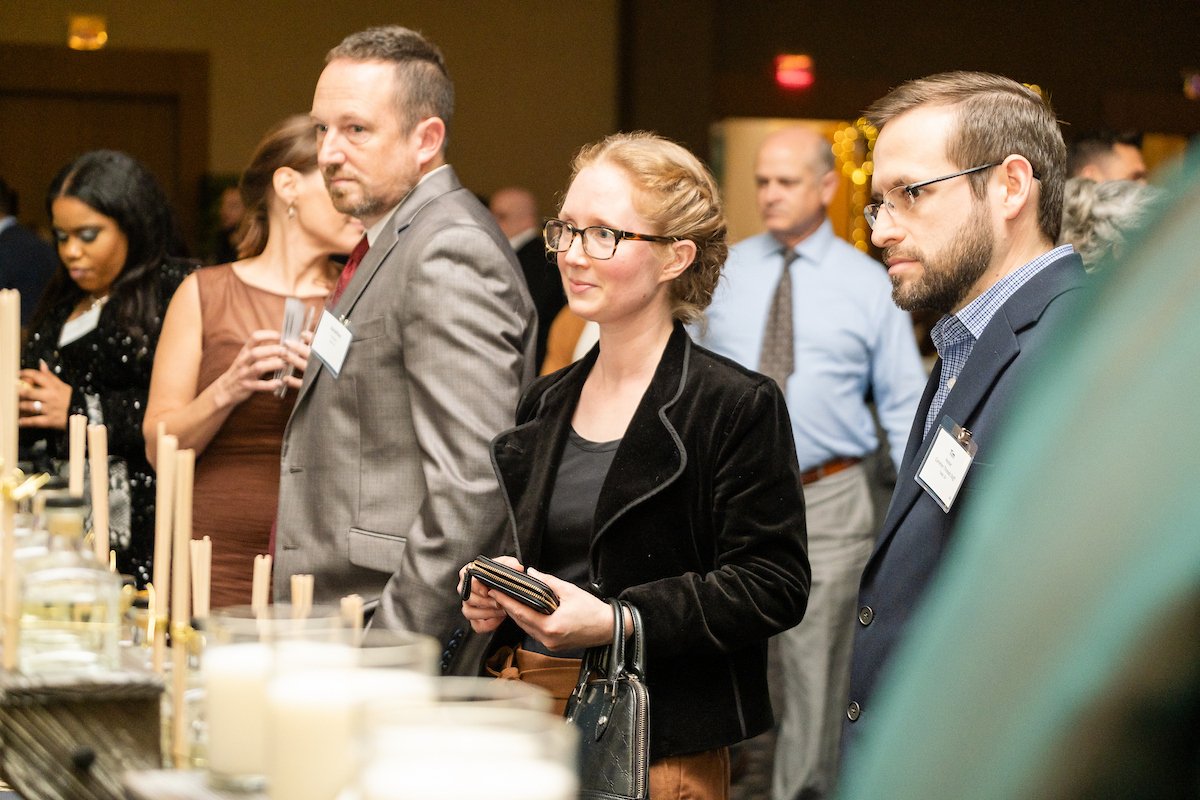 A woman with glasses and strawberry blonde hair eagerly waits in line to purchase a candle at a nonprofit fundraiser