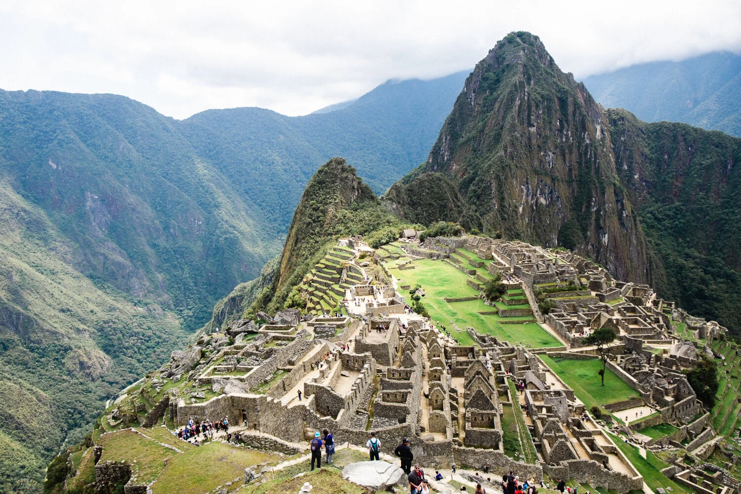 Historic Incan ruins of Machu Picchu with stone structures and terraces set against lush green mountains.