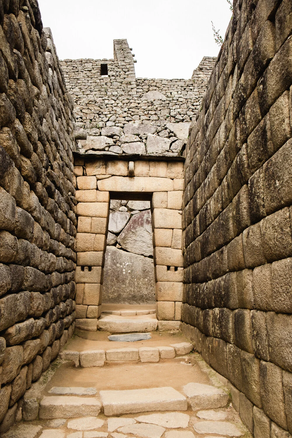 Stone ruins at Machu Picchu with a stone doorway, staircase, and stone walls.