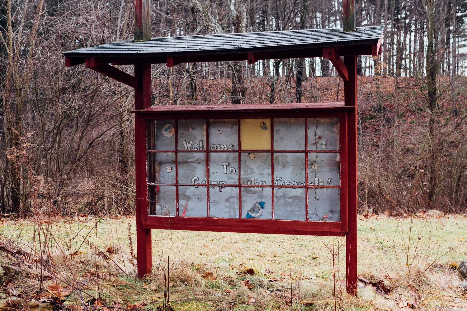Wooden welcome sign board with a glass cover displaying the text "Welcome to Coppola Gravelly" in a wooded outdoor area.
