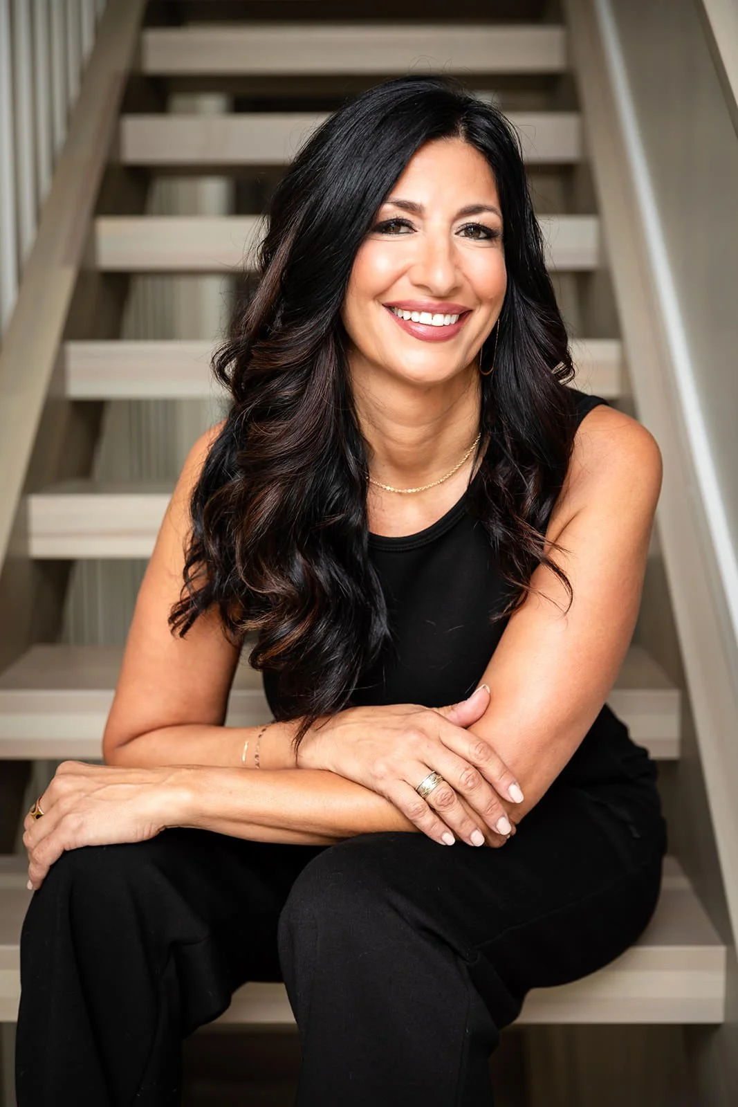 Frances DiBello, a consultant with expertise in manufacturing and private equity, seated on stairs in a relaxed pose, showcasing confidence and authenticity.