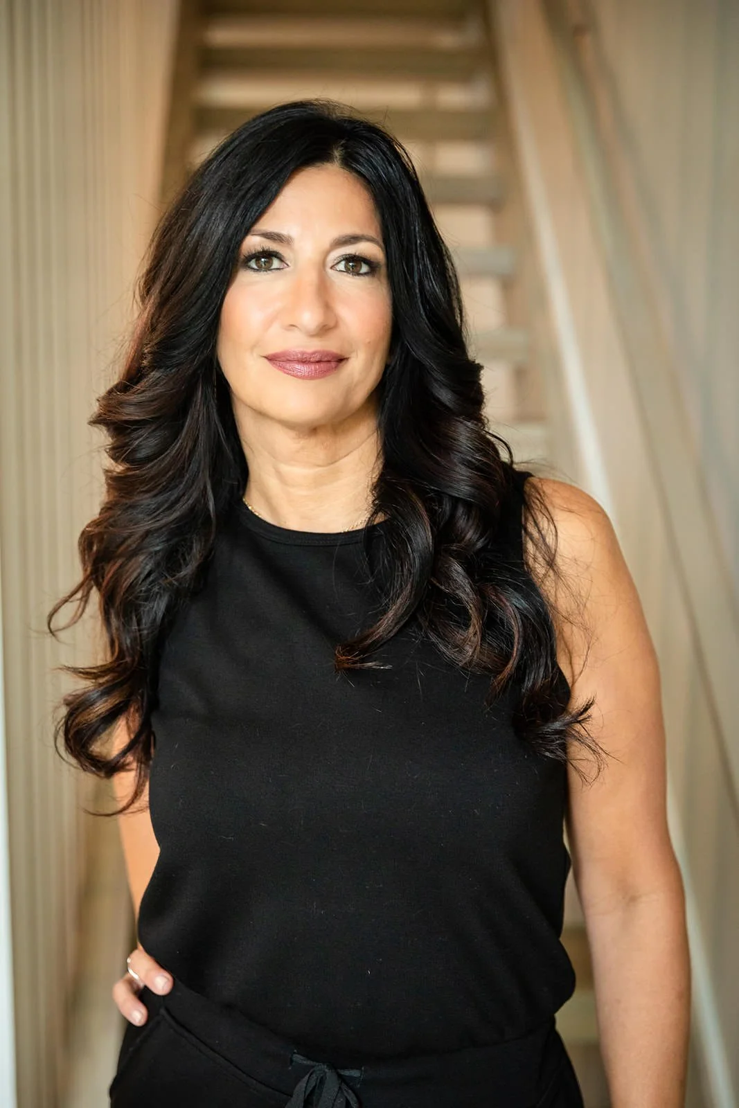 Frances DiBello, expert in IT and business strategy for manufacturing and private equity, standing confidently on a staircase in a sleek black outfit, reflecting professionalism and poise.