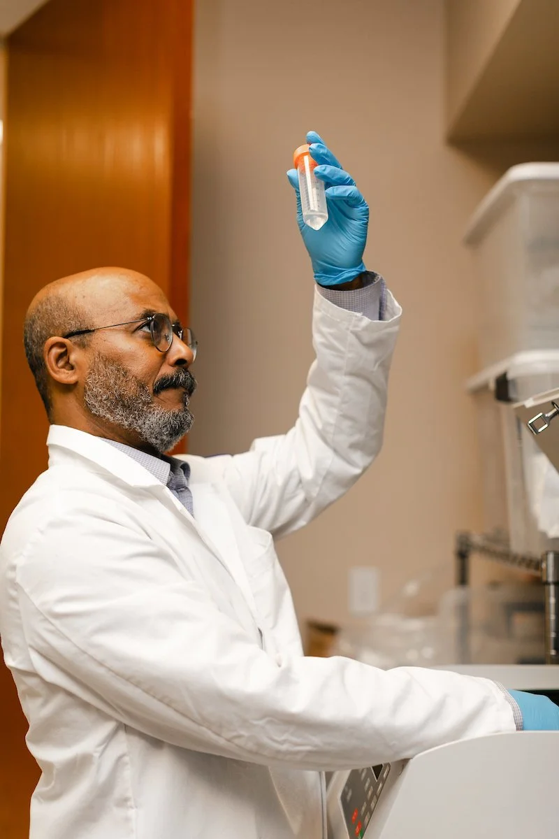 A scientist in a lab coat and gloves carefully examining a test tube with a cancer cell sample at SageMedic's state-of-the-art laboratory, advancing personalized chemotherapy research.