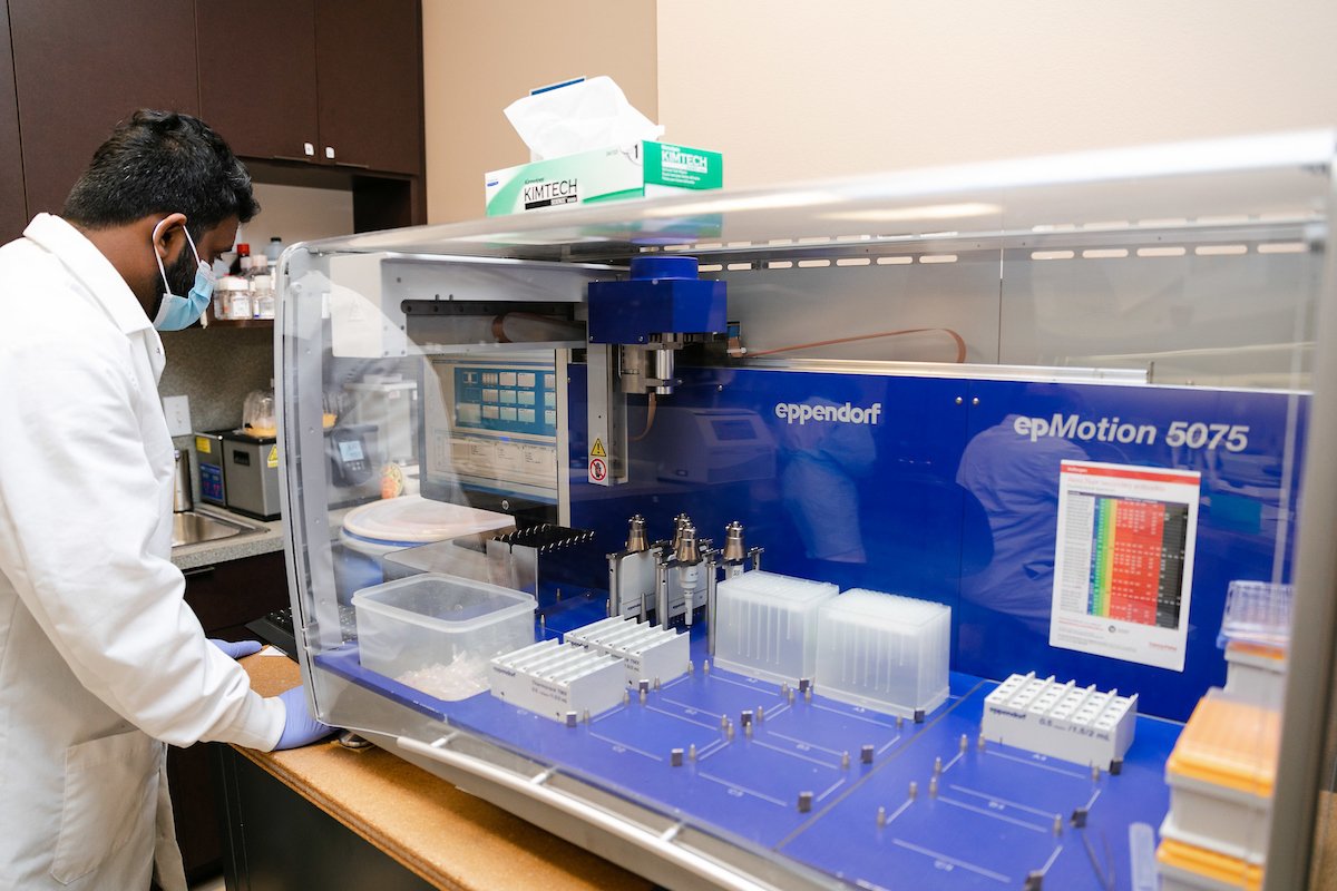 Laboratory technician operating the Eppendorf epMotion 5075 automated liquid handling system for precision testing and sample preparation in the SageMedic research facility.