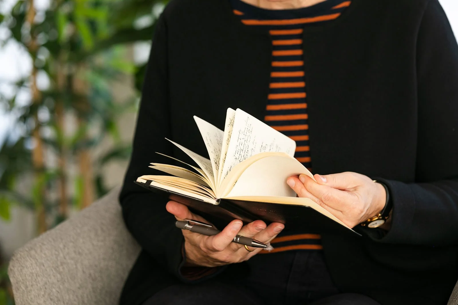 Close-up of Dr. Brigitte Apfel’s hands flipping through a handwritten notebook—capturing the reflective, human-centered approach behind her trauma-informed psychiatric care and personal brand story.
