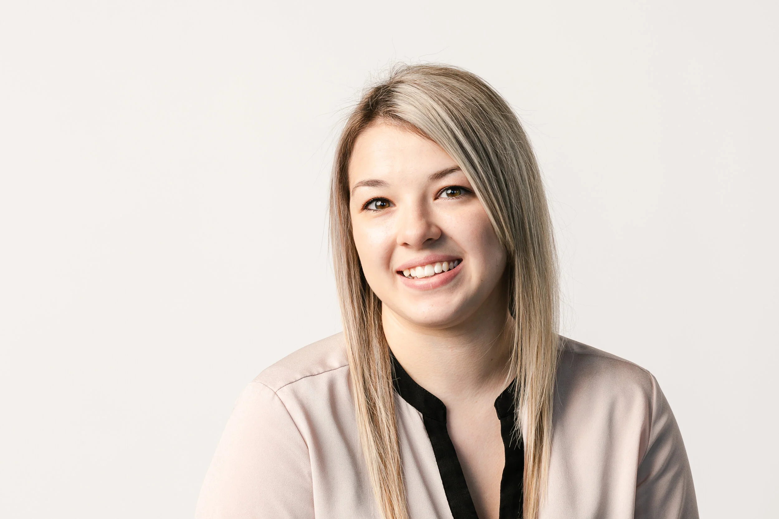 Blonde woman posing for headshot in blush-colored blouse.