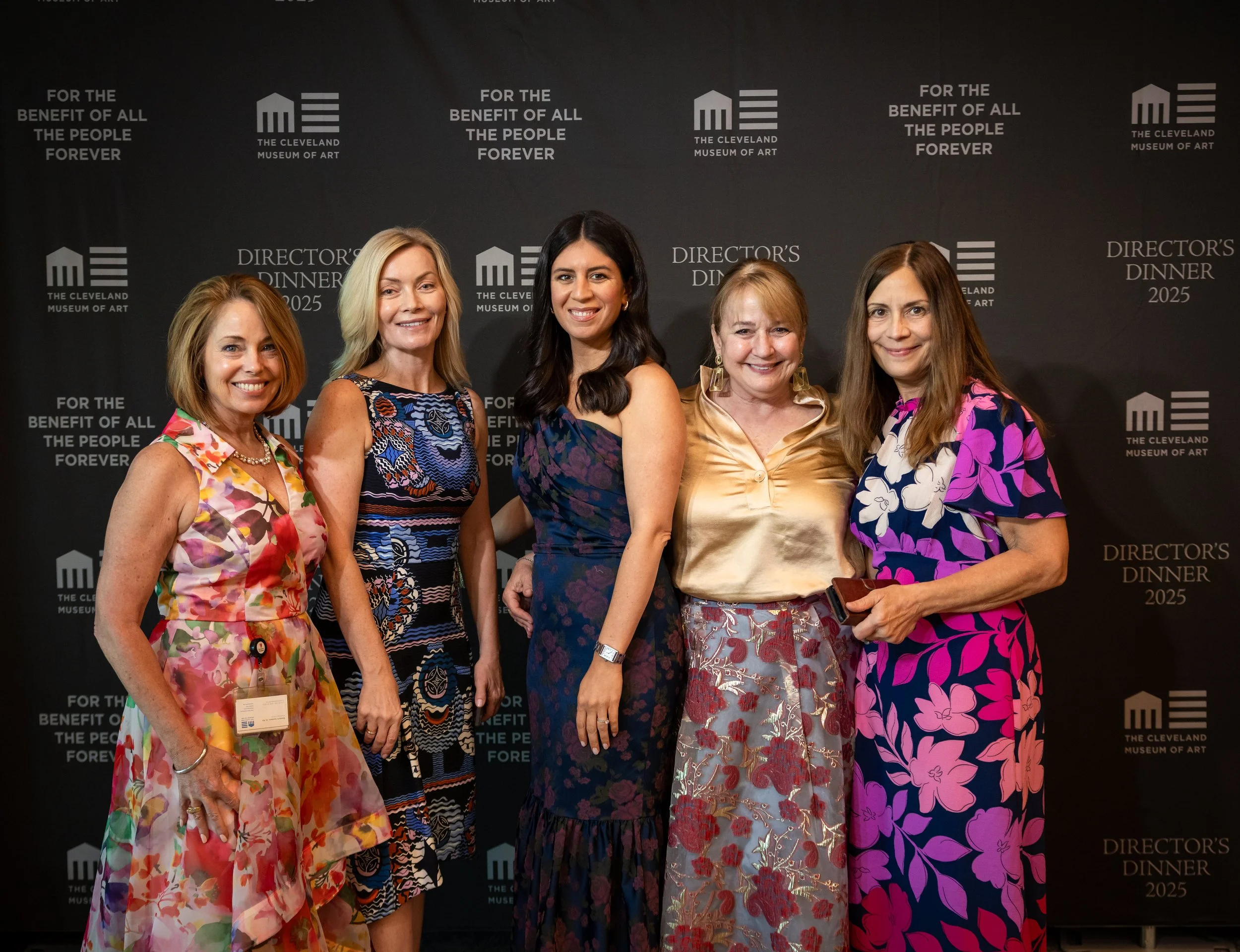 A well-dressed group of women wearing colorful ballgowns pose against a step-and-repeat to get their photo taken at th eRunway to Renaissance event at the Cleveland Museum of Art's opening ceremony.
