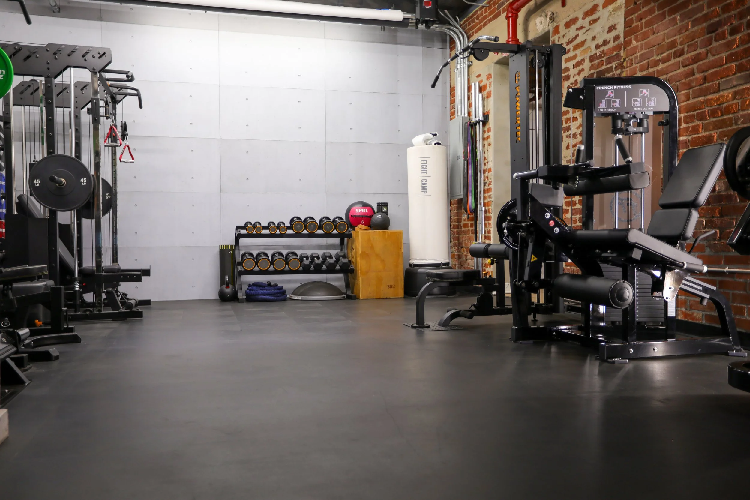 Open floor plan private fitness studio in Los Angeles with free weights, selectorized machines, and dedicated training zones in a luxury gym environment.