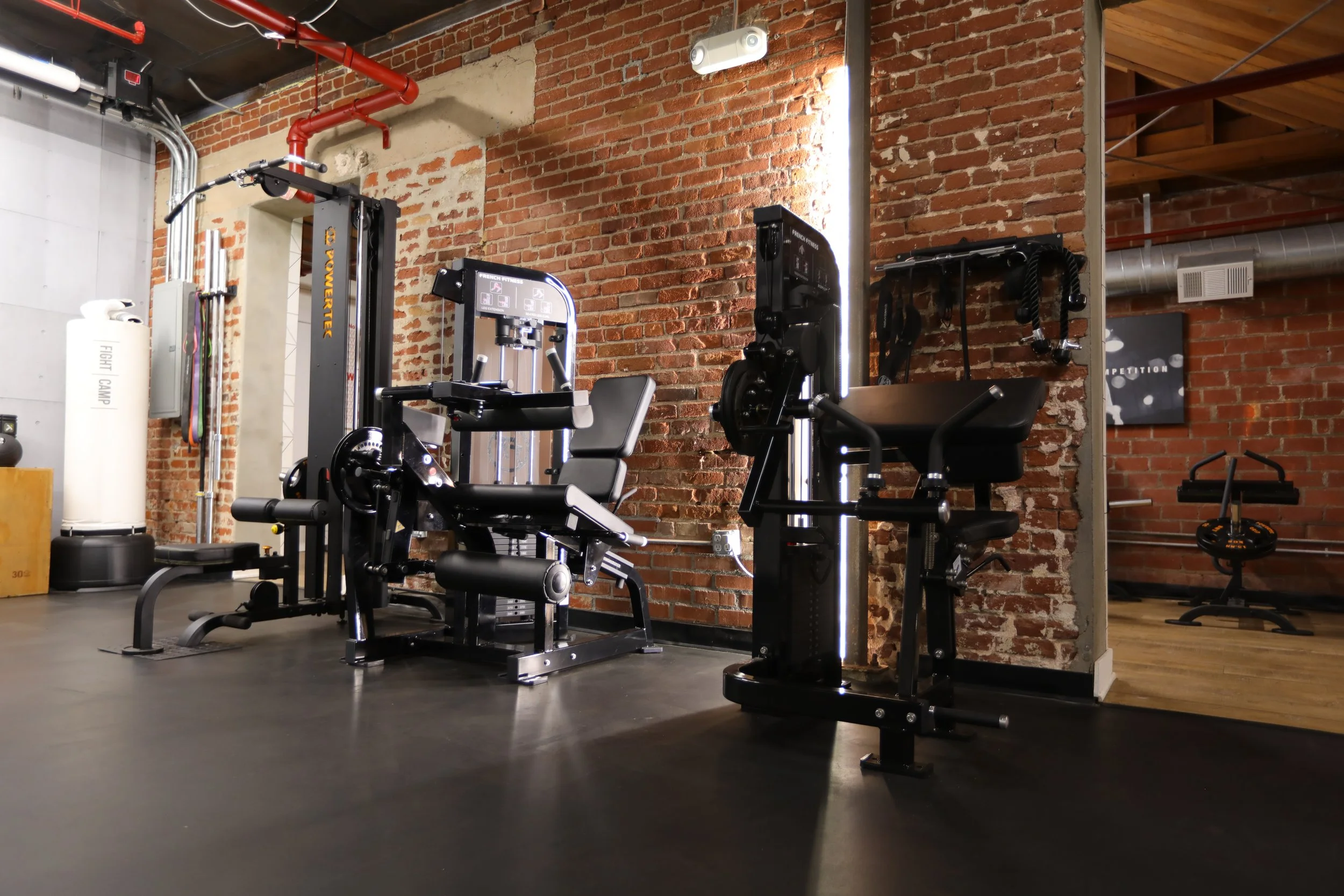 Gym with workout equipment, brick wall background, exercise machines, and weights.