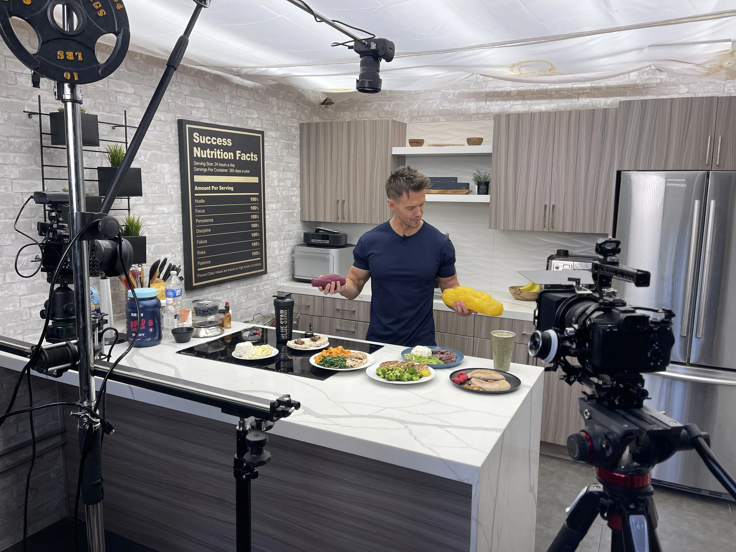 Professional fitness and nutrition content filming setup in a private Los Angeles studio with cameras, lighting equipment, and modern kitchen set.