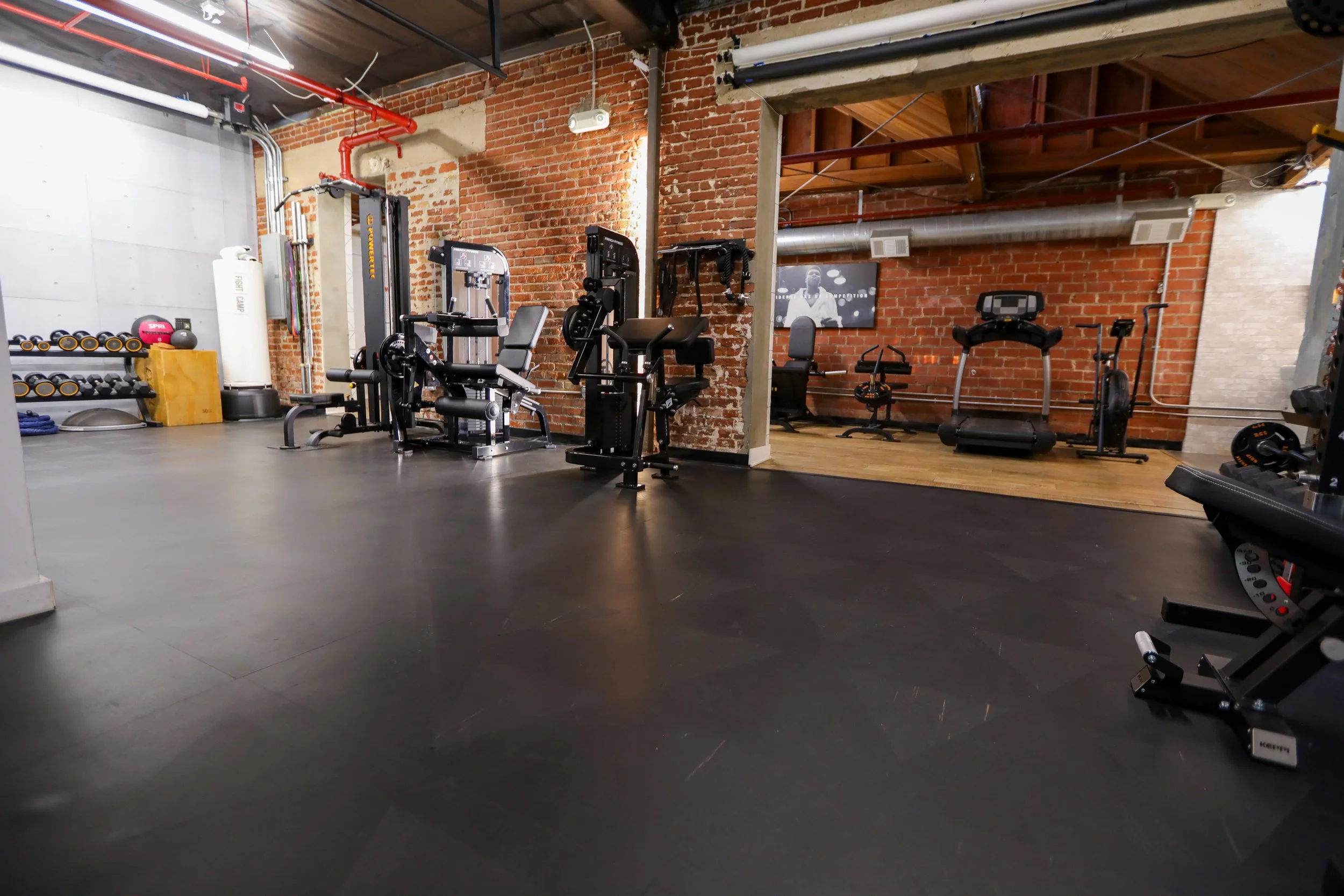 Industrial loft-style private fitness studio in Los Angeles with exposed brick walls, open training floor, and premium gym equipment for personal training and content creation.