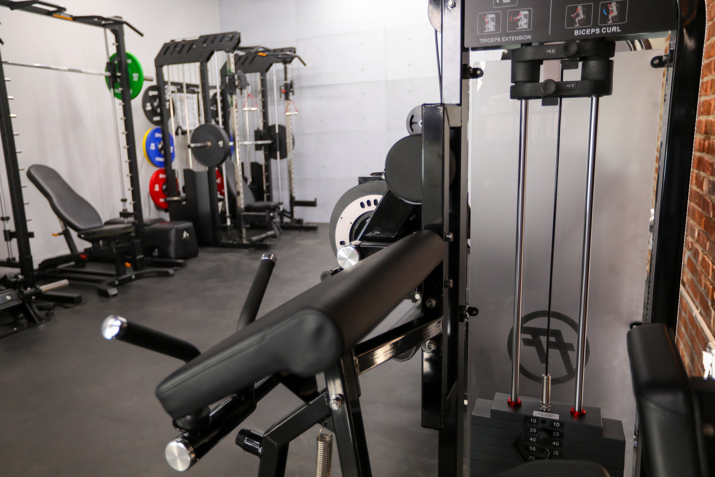 Fitness equipment in a gym including a workout bench, various weightlifting machines, and weight plates.