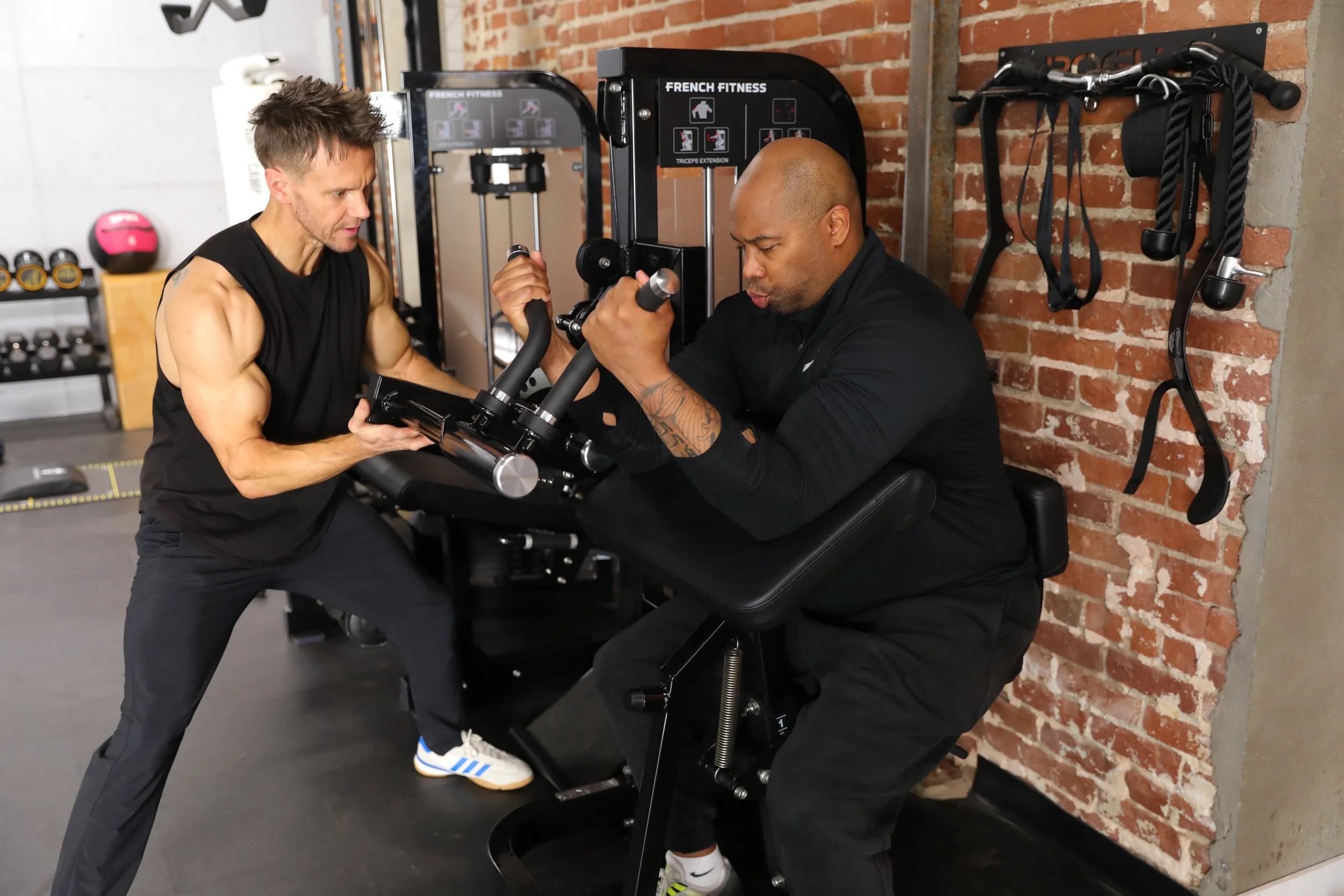 Private personal trainer Rob Riches coaching a client during an arm exercise in a fully equipped private training studio in Los Angeles.