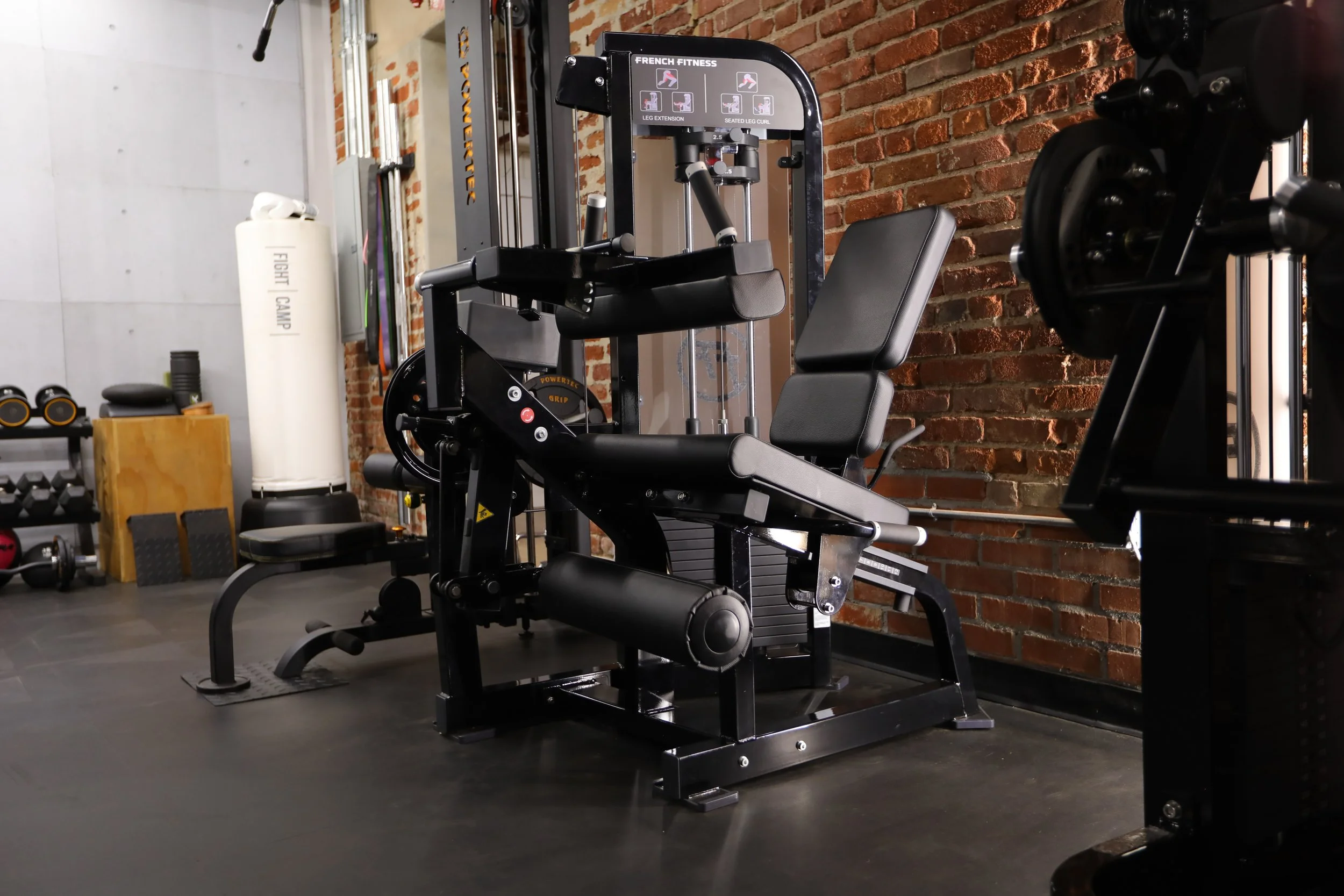 Selectorized strength training machine in a private Los Angeles fitness studio with exposed brick wall and professional gym equipment.