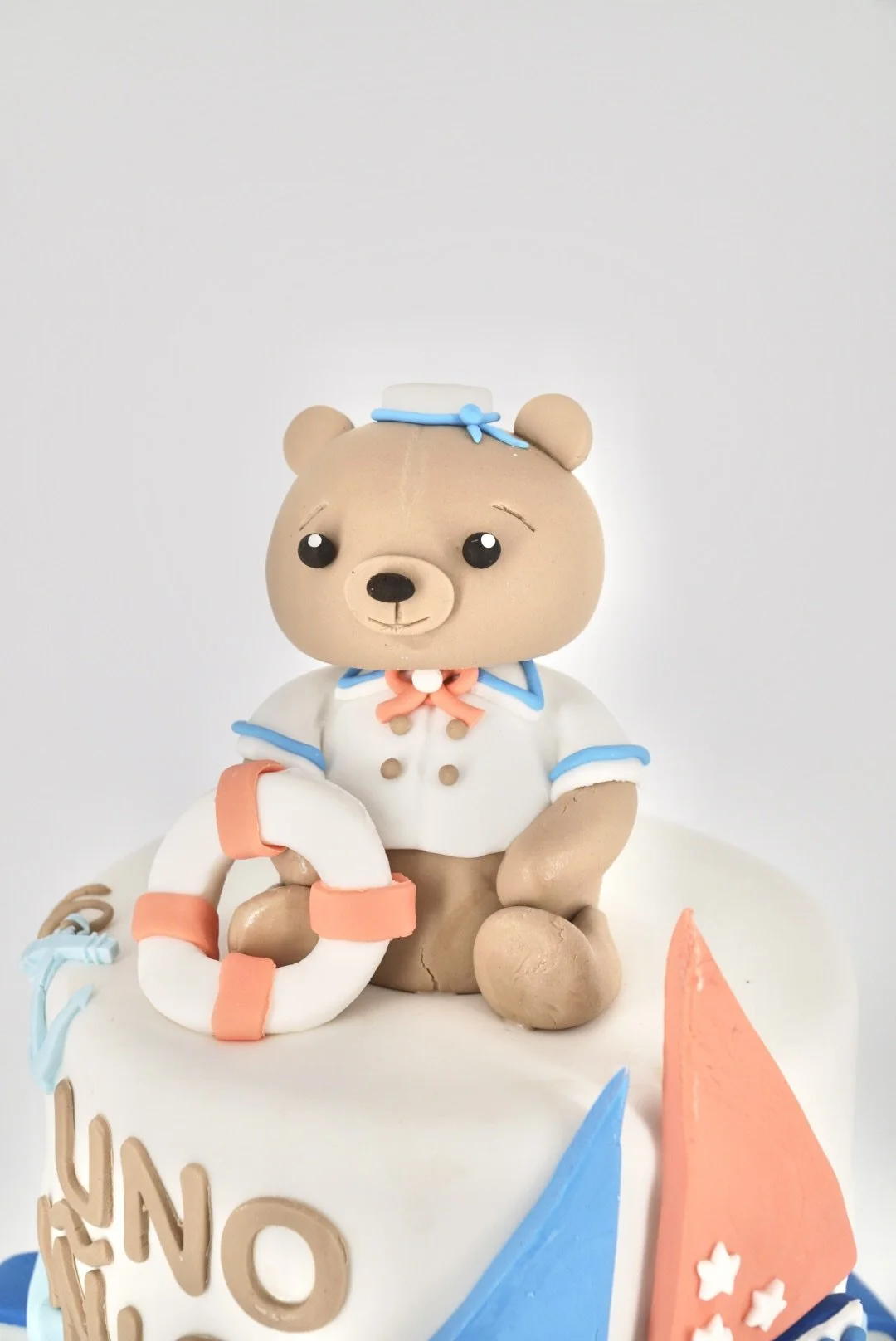 Two-tiered white wedding cake decorated with white flowers and small white pearl-like beads, on a white cake stand.