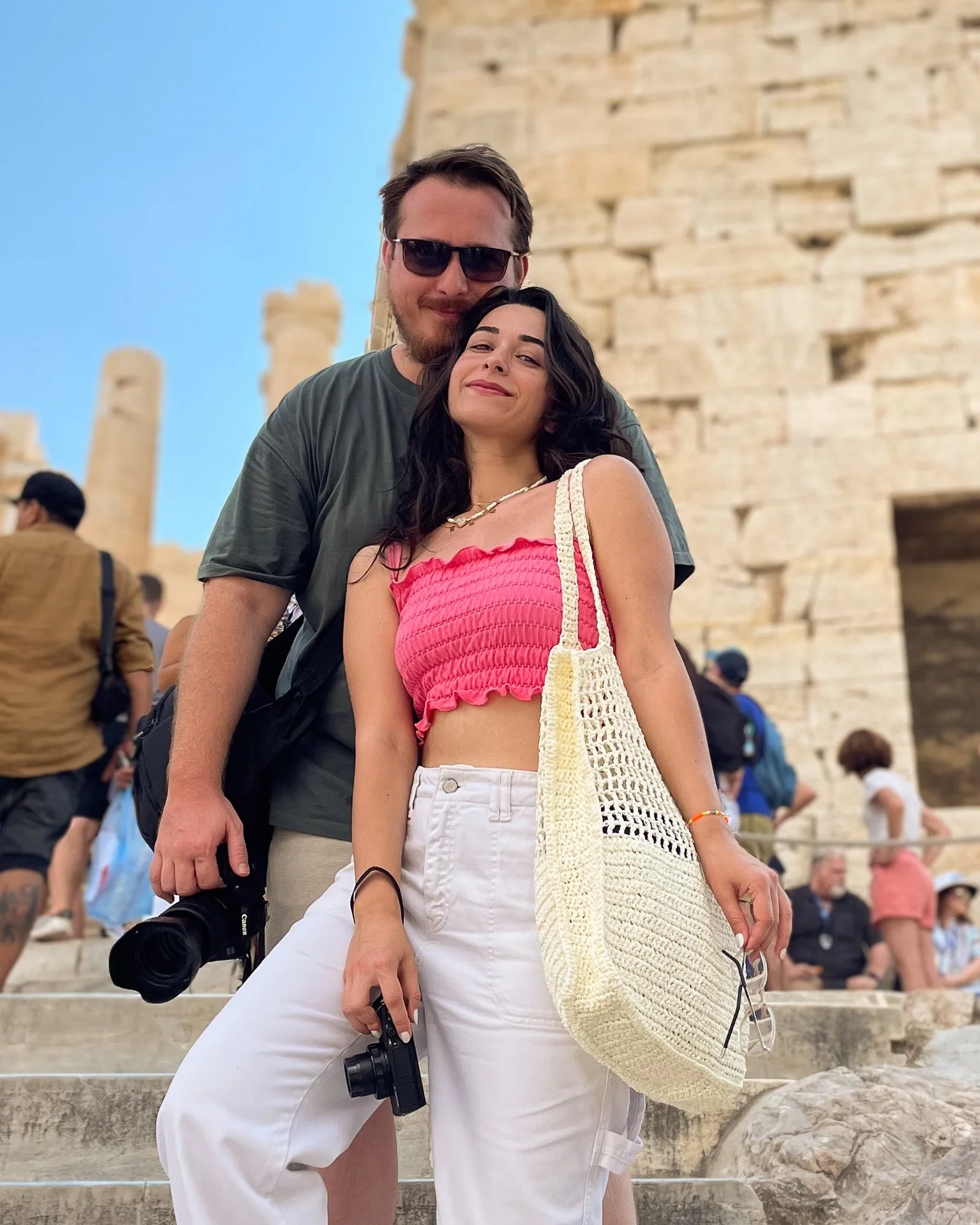 A couple posing together in front of an ancient stone structure, possibly at a historical site or monument.