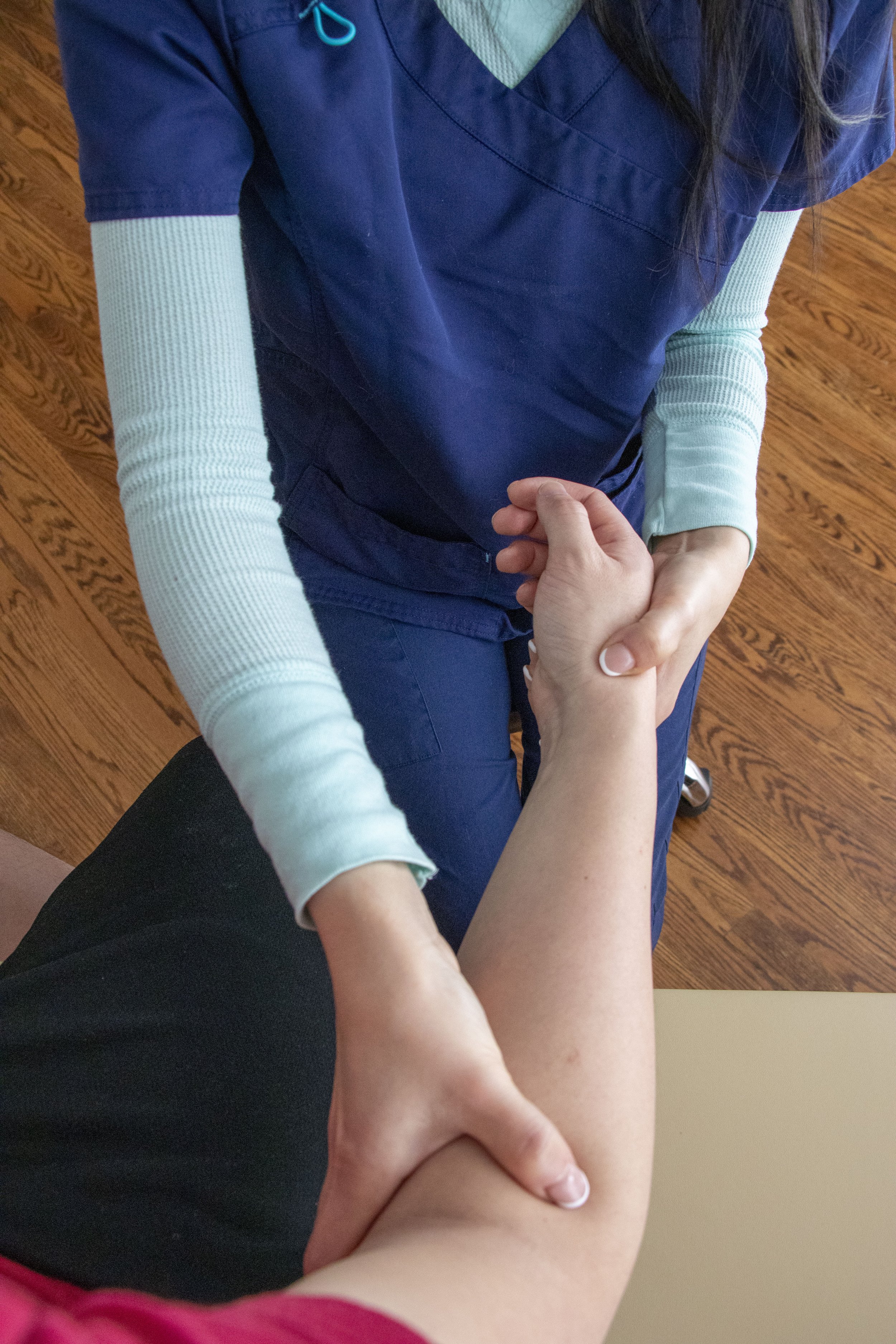 A healthcare professional is examining a patient's arm during a medical checkup, and providing osteopathic treatment to the arm.
