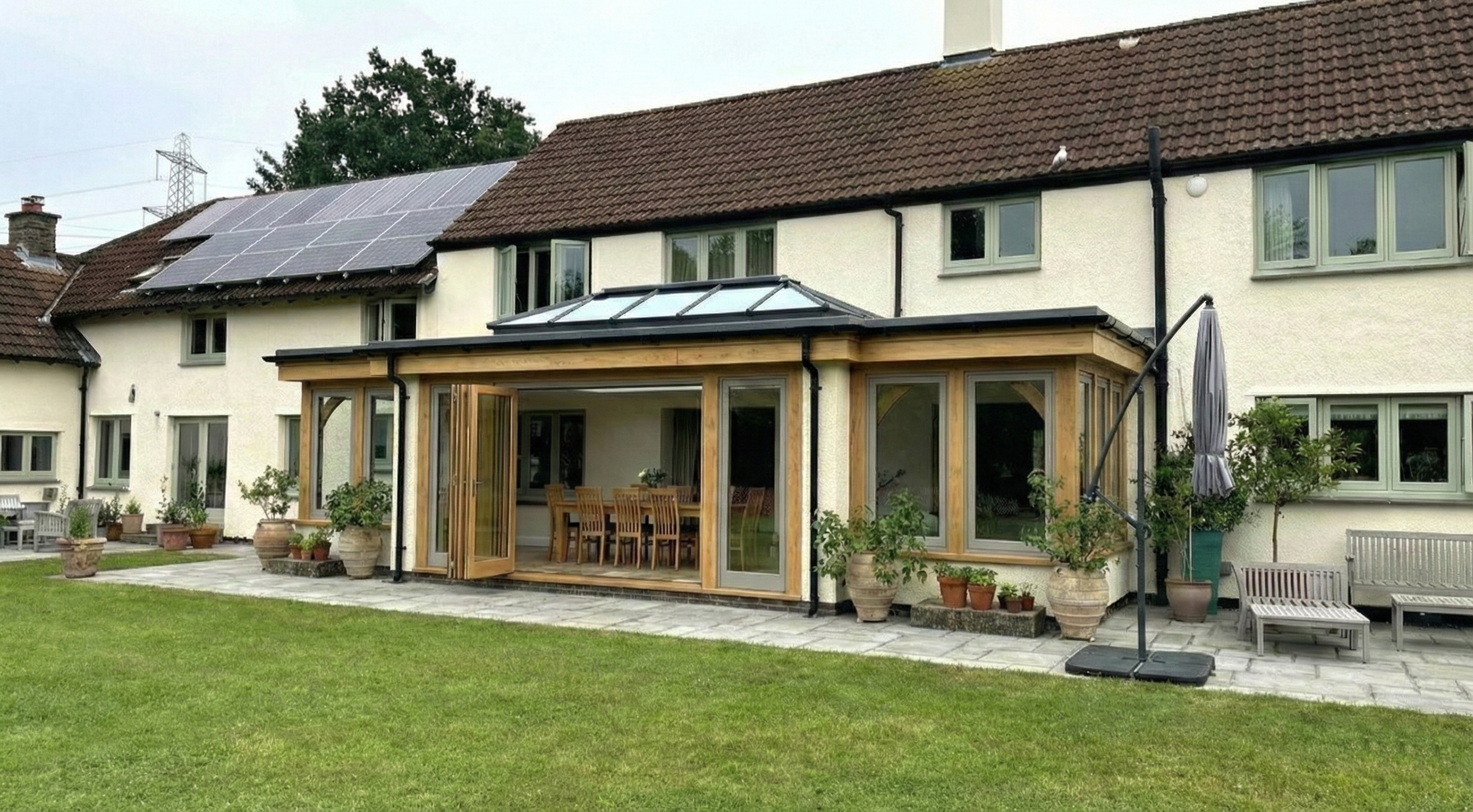 Modern oak orangery featuring light grey aluminium windows and traditional timber frame construction