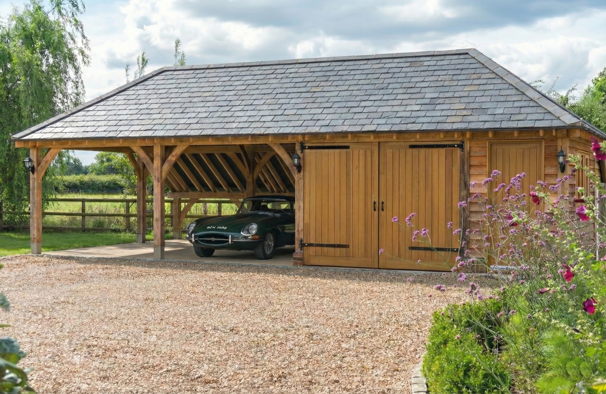 Bespoke oak framed garage housing a classic car, showing traditional opening timber doors