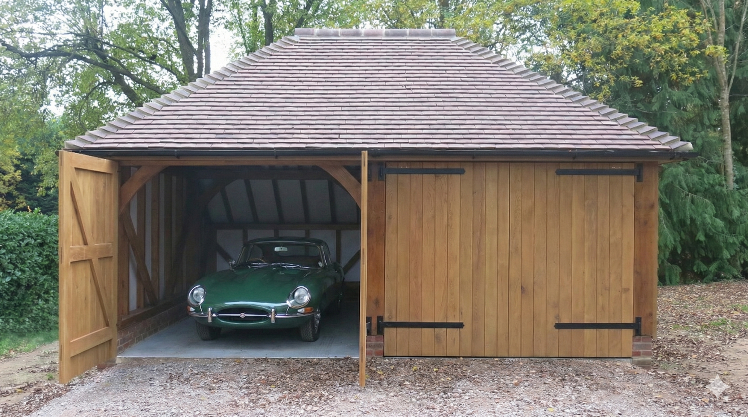 A wooden garage with a partially open door reveals a vintage green car inside, surrounded by trees and foliage.