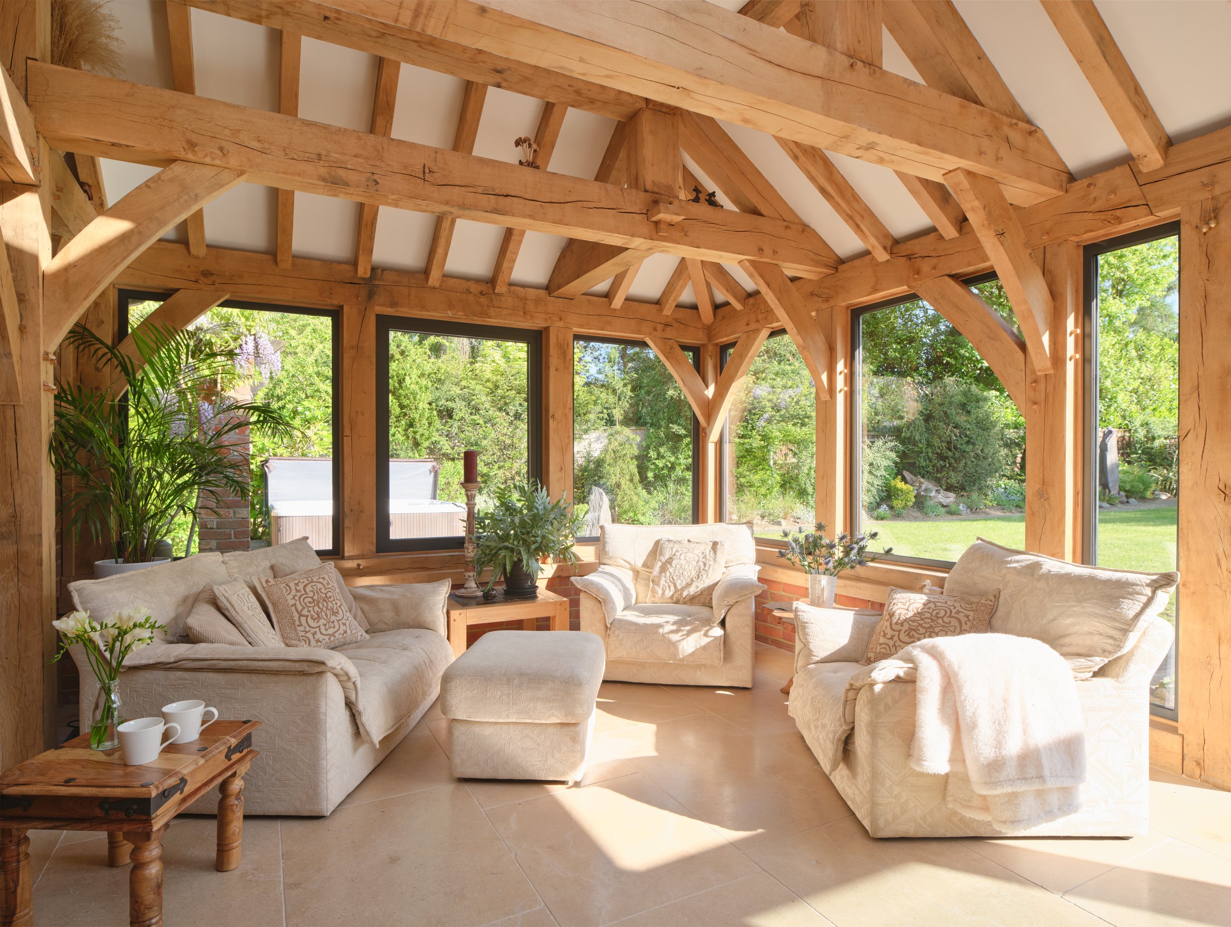 Sunlit luxury oak orangery with large windows and cozy interior furniture