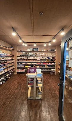 Bookshelves filled with books and magazines in a cozy bookstore with warm lighting and wooden floors.