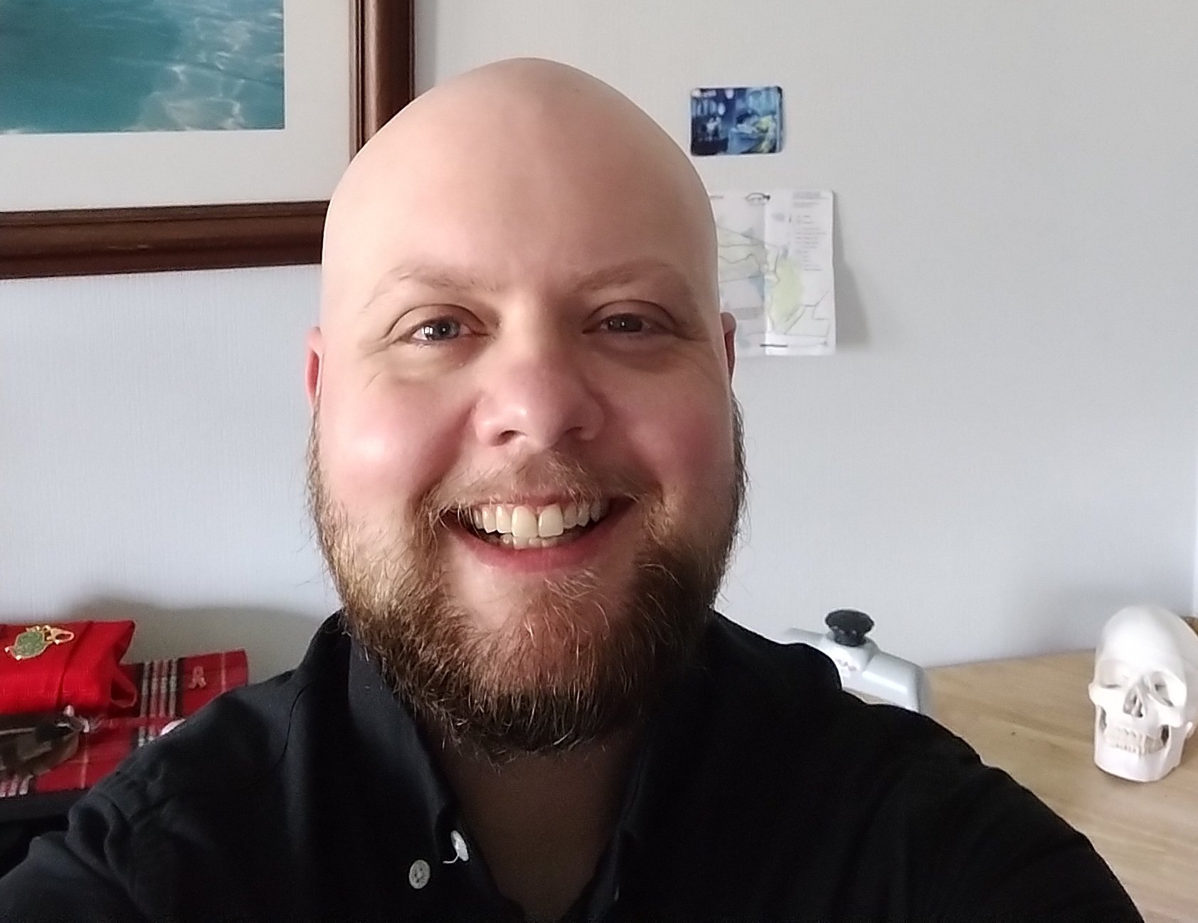 Meghan Morrison, a licensed massage therapist in Merrimack, NH. They are a transmasculine non-binary professional with a warm smile and neat beard.