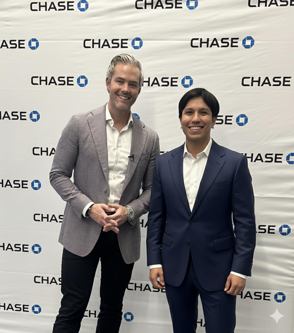 Dos hombres vestidos con traje posan para una foto delante de un fondo con la marca Chase Bank.