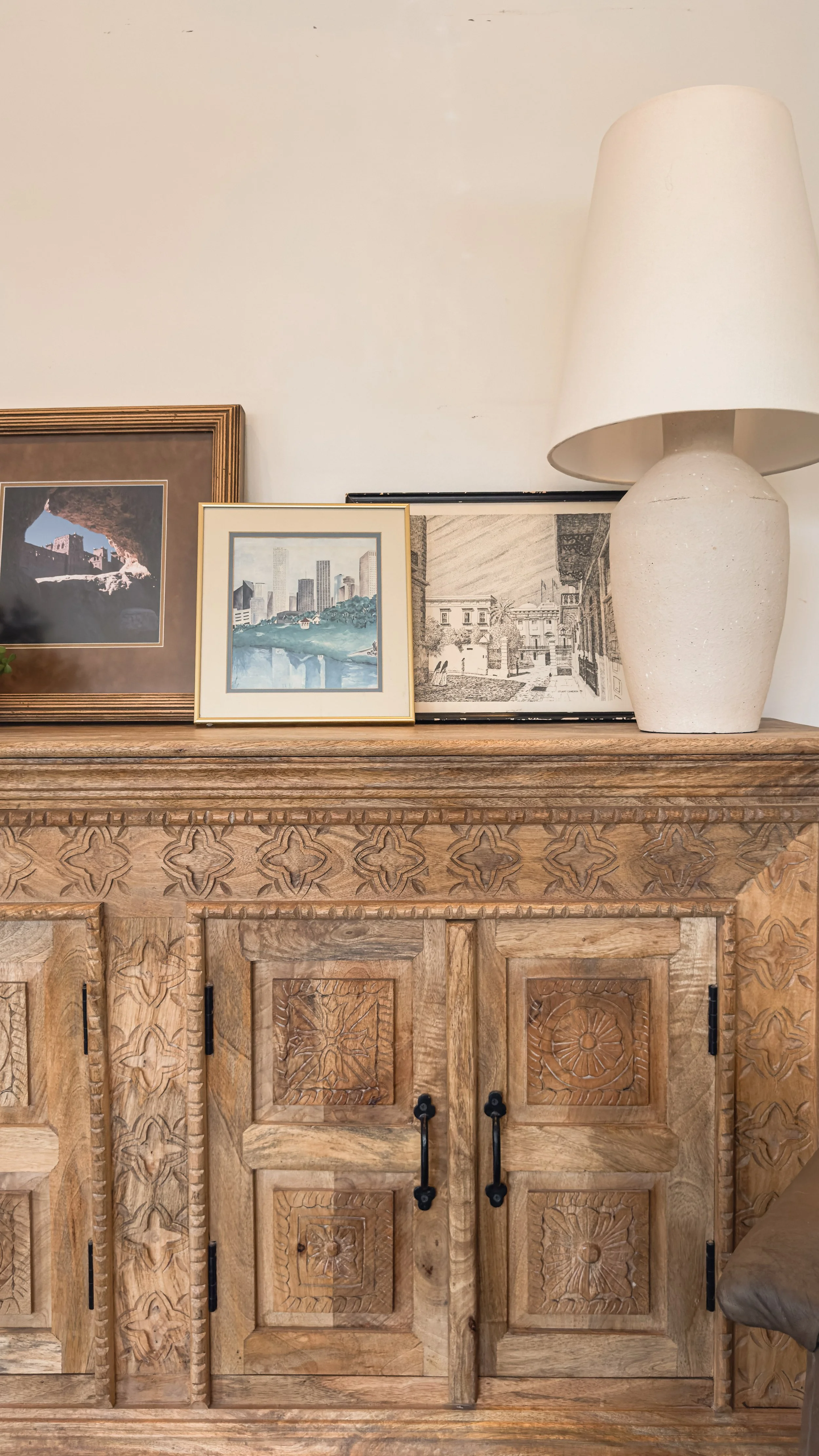 Interior detail with framed artwork, sculptural ceramic lamp, and carved wood credenza at the Emerson residence.