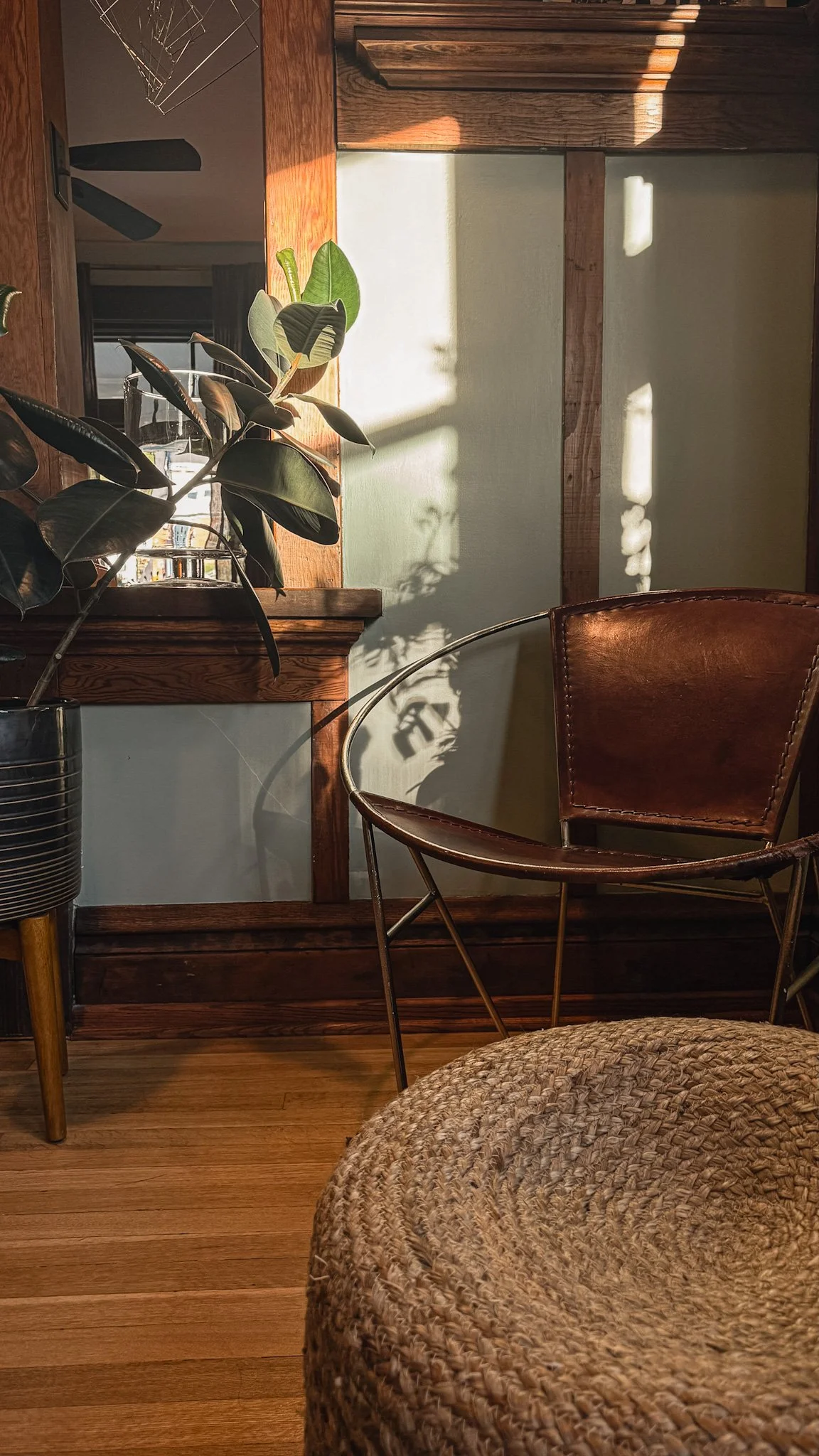 Sunlit interior at 930 South in Salt Lake City with a leather chair, natural wood trim, houseplant, and woven foreground texture.