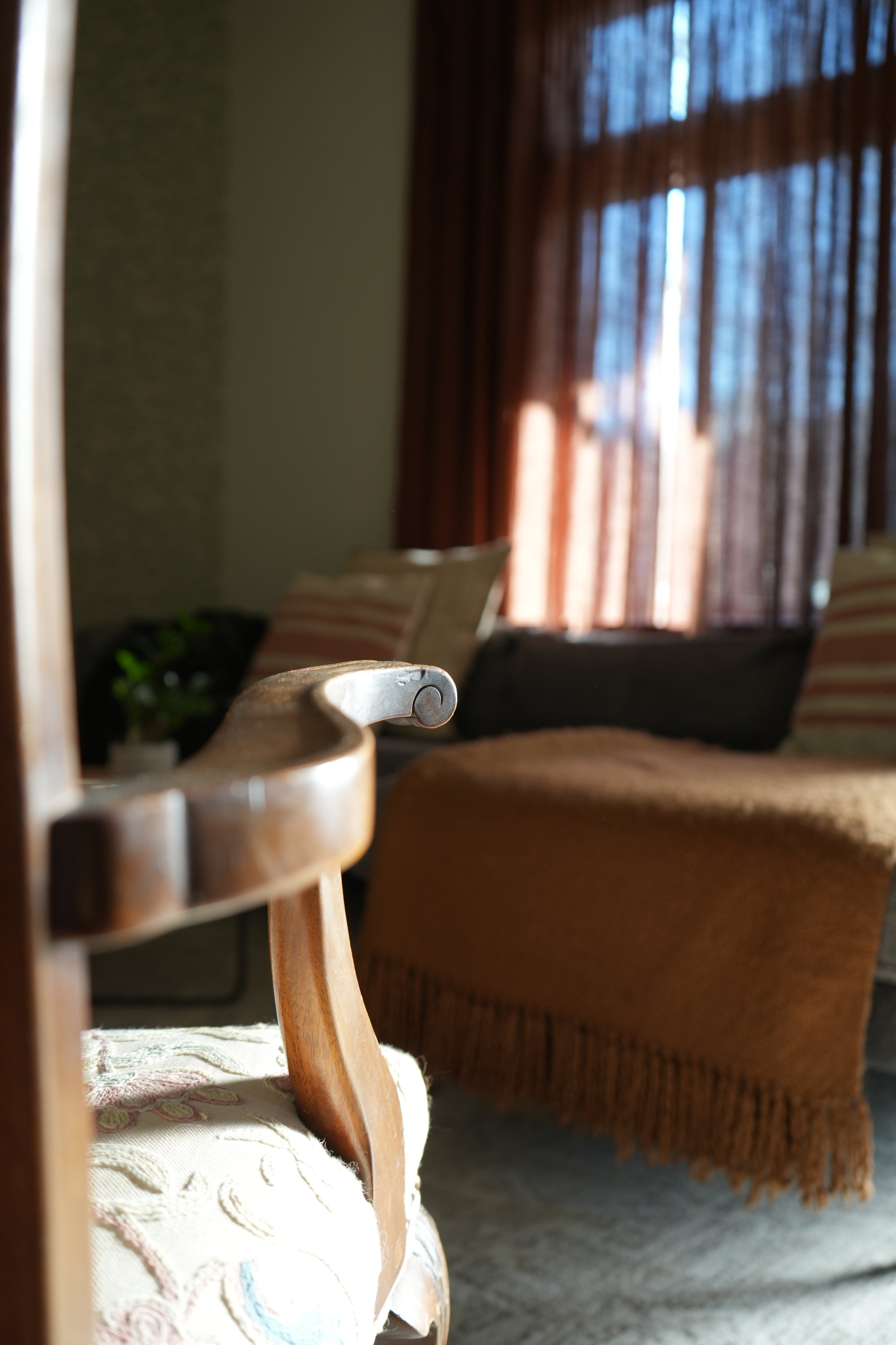 Quiet sitting area at the 930 South residence with warm wood, upholstered seating, and soft natural light.
