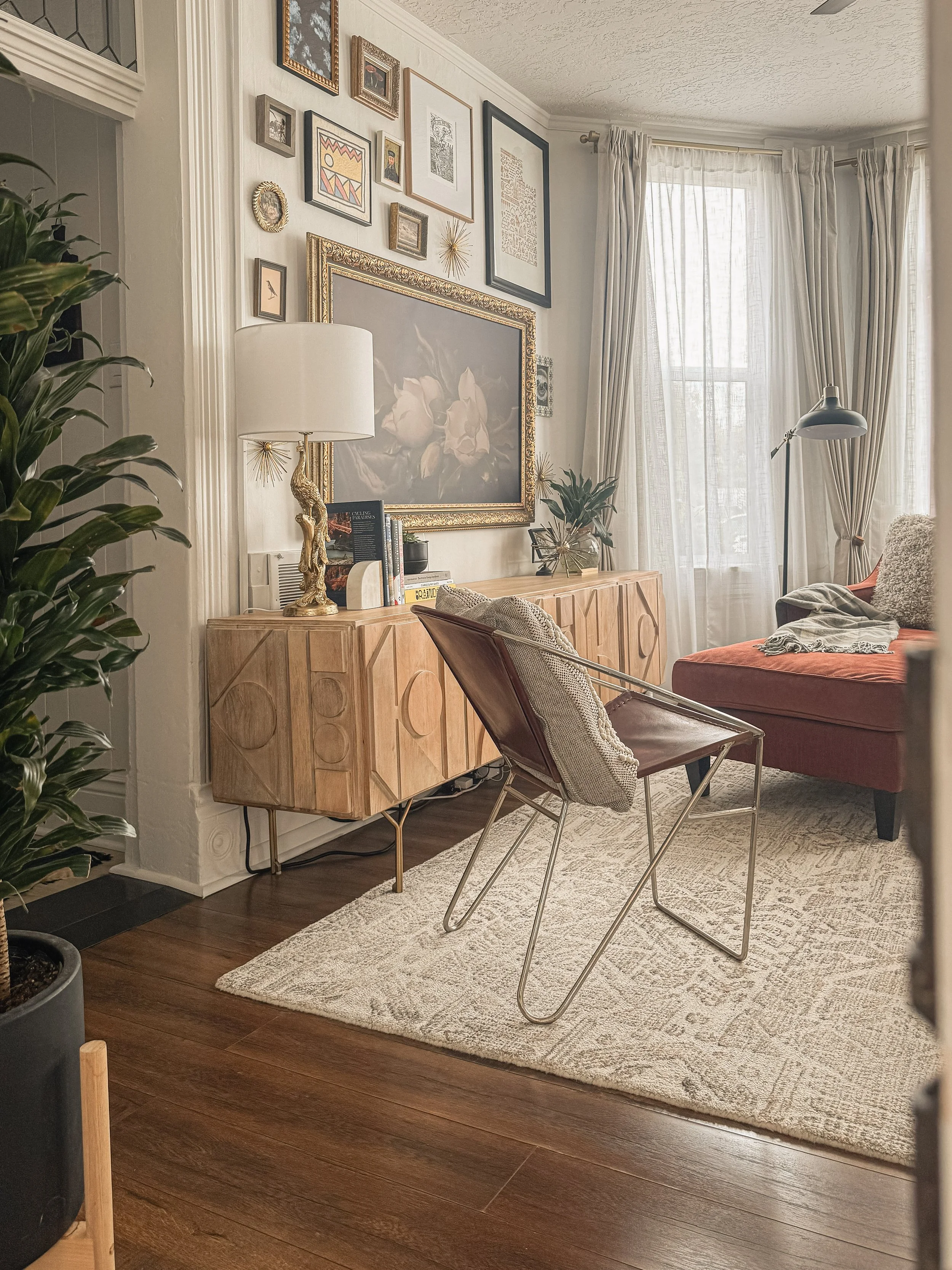 Living room at the West Temple residence in Salt Lake City with warm wood flooring, layered artwork, sculptural furniture, and natural window light.