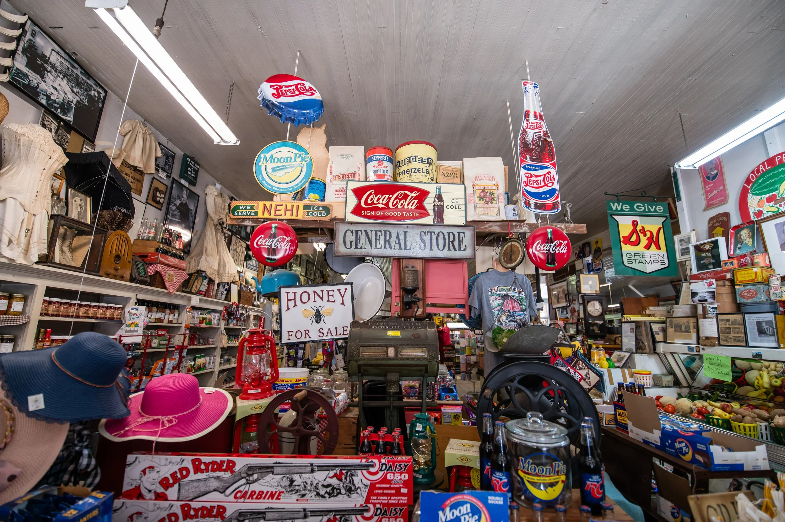 Interior of a vintage general store decorated with nostalgic signs, vintage toys, and collectibles, including Coca-Cola advertising and old-fashioned items.