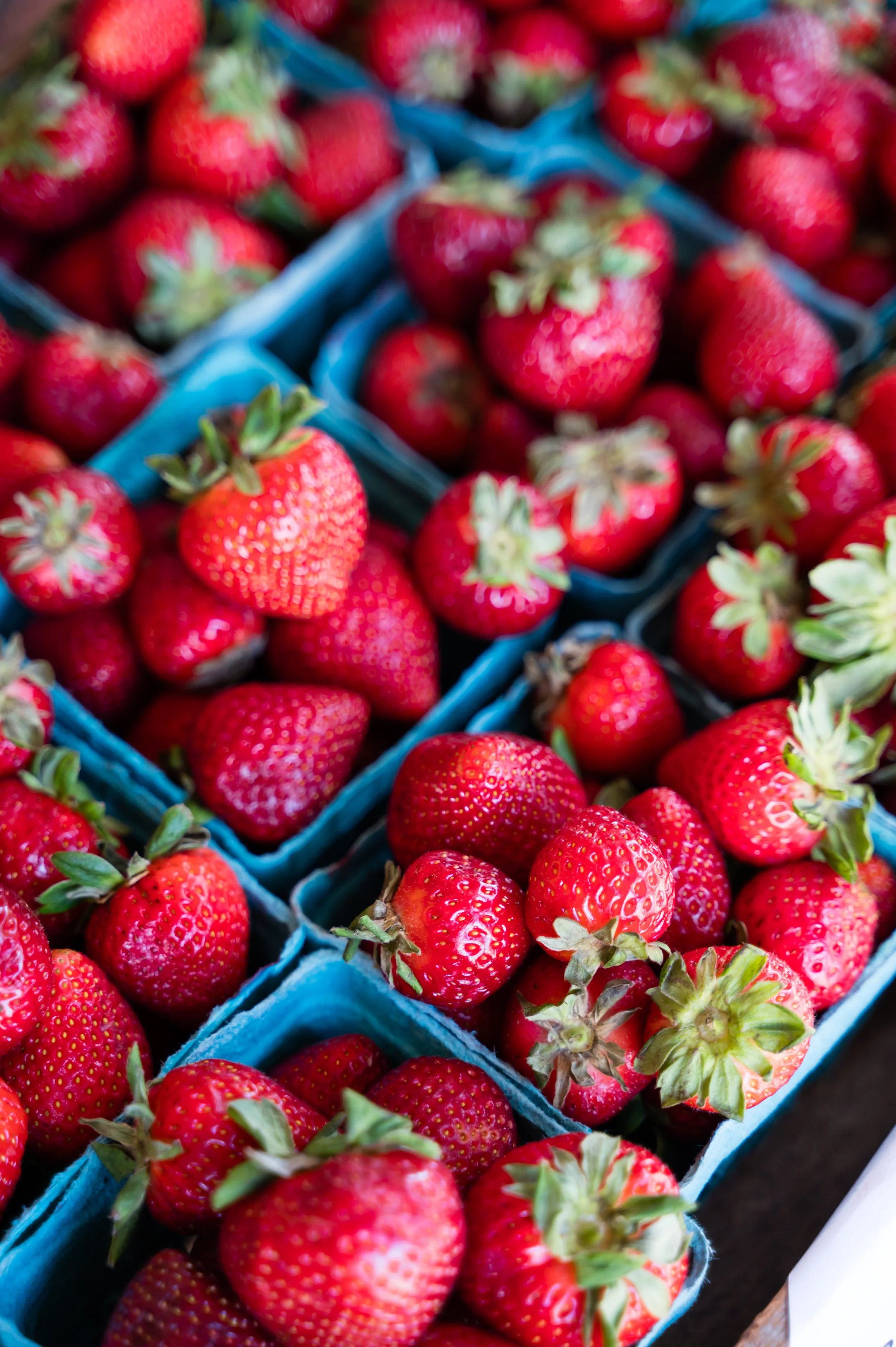 Fresh strawberries in blue containers at a market.