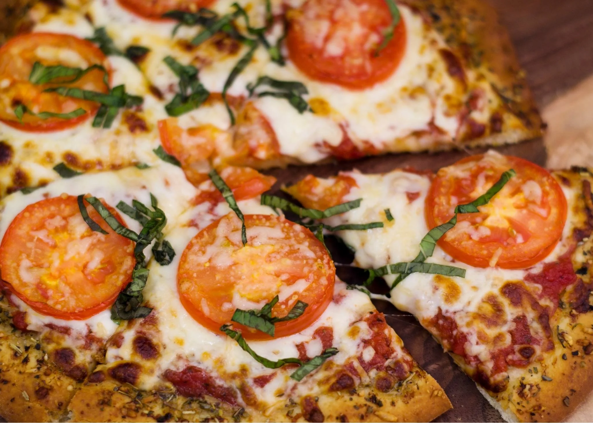 Close-up of multiple slices of pizza topped with tomatoes, cheese, basil, and various seasonings.